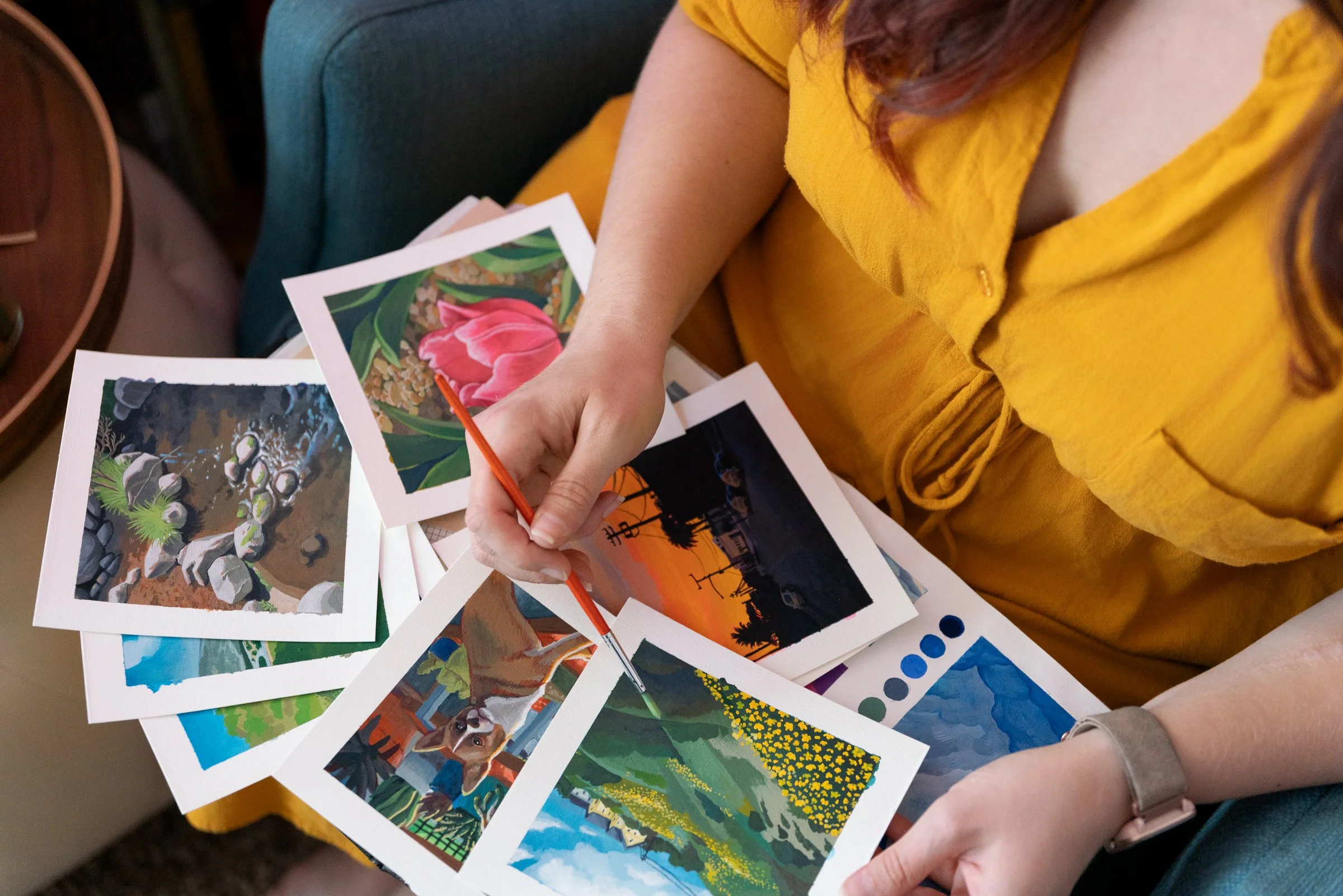 Close-up of Leah's hands fanning out a set of her original watercolor paintings.