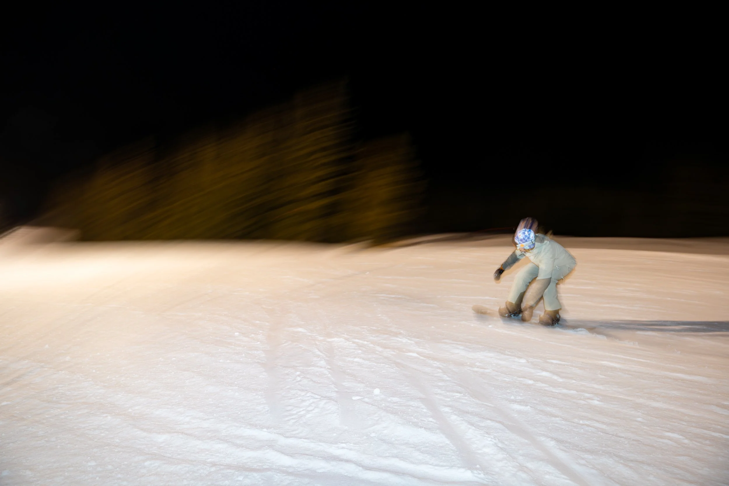 Person snowboarding on a snowy slope at night