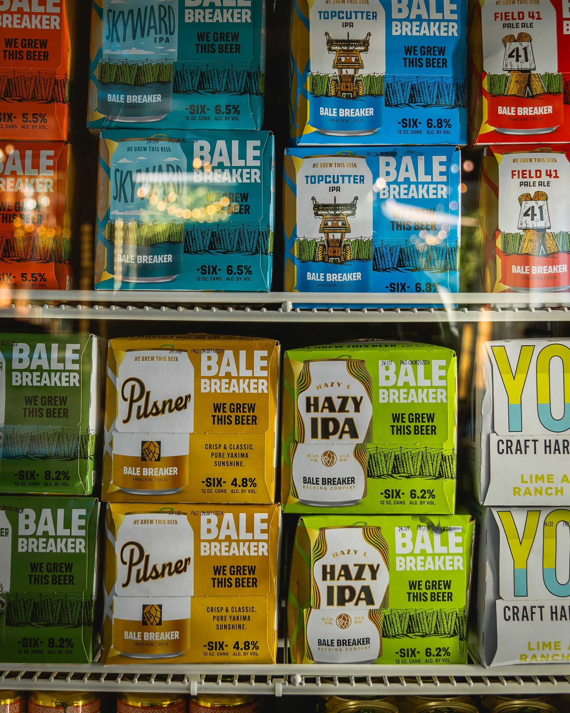 Shelf of beer cans with colorful packaging, including Bale Breaker beers such as Skyward IPA, TopCutter IPA, Field 41 Pale Ale, Pilsner, Hazy IPA, and Lime Ranch craft hard seltzer.