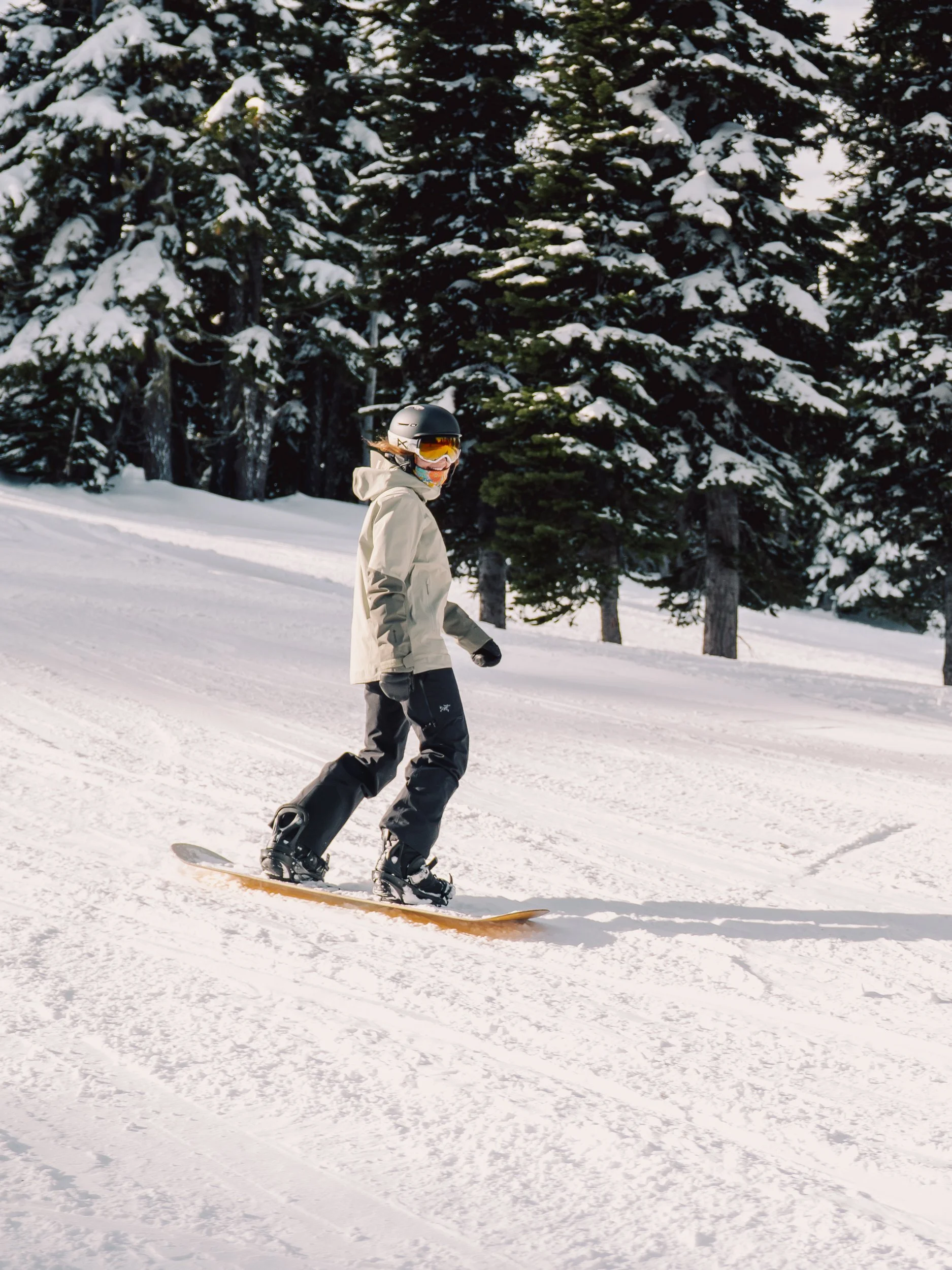 A person snowboarding on a snowy slope surrounded by pine trees.