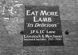 Vintage advertisement painted on brick wall promoting lamb meat, reading "Eat More Lamb, 'It's Delicious' J.P. & J.C. Lane Livestock & Merchants, Ketchum & Sun Valley 1915-1980."