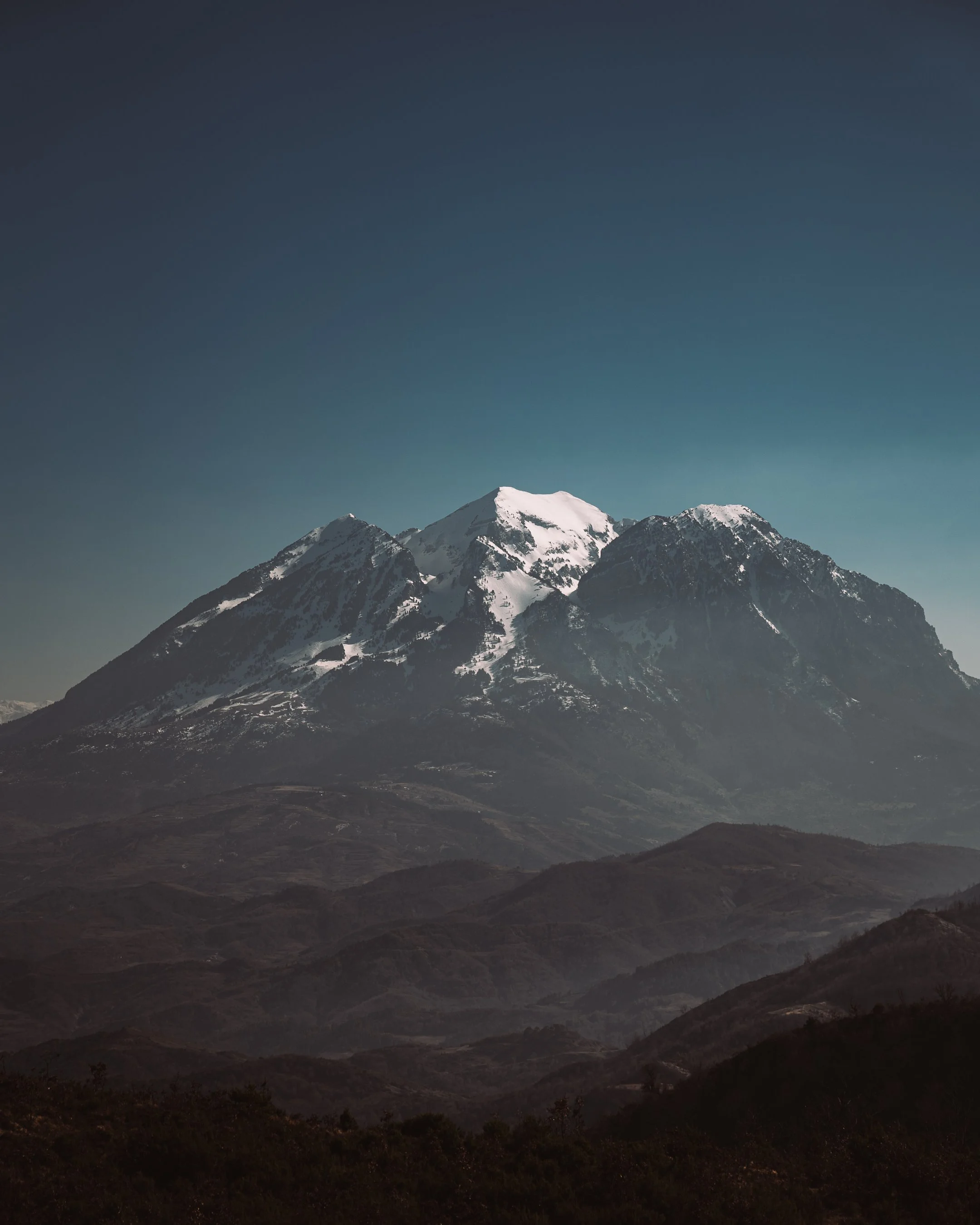 Snow-capped mountain with clear sky backdrop.