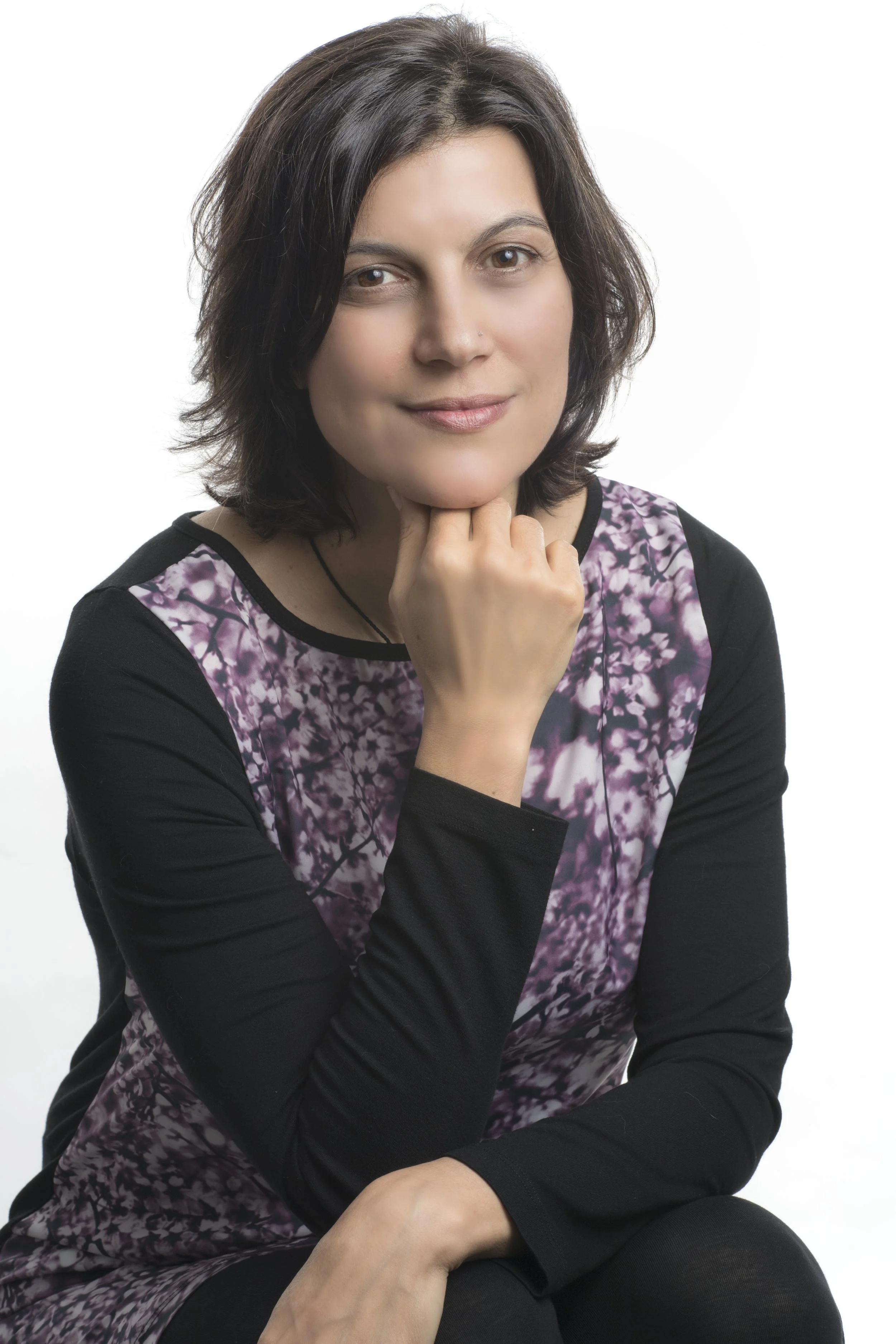 A woman named Victoria with dark hair wearing a purple top, smiling confidently in a bright setting.