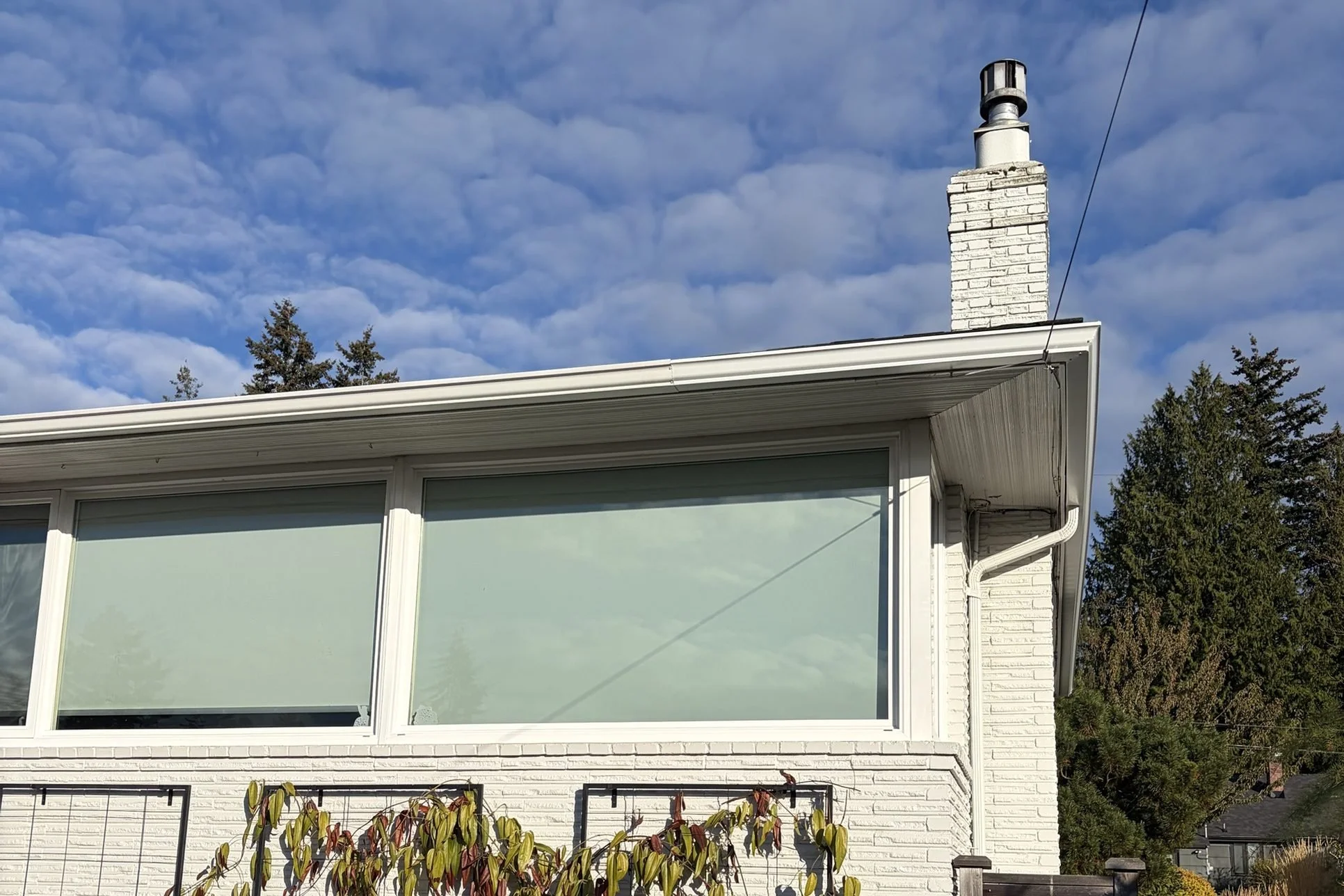 White brick Broadview rambler with a clean white gutter along the roofline under a blue sky.