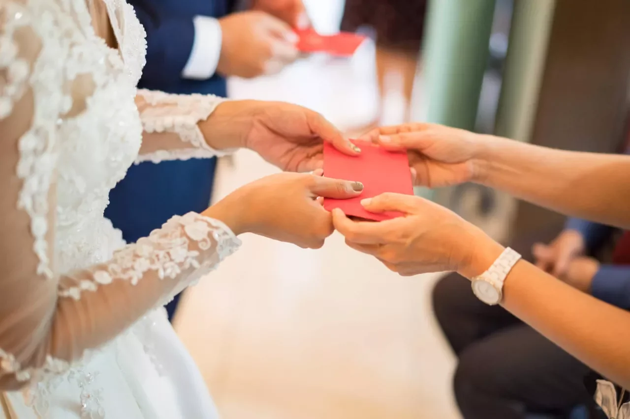 bride handing mother red envelope on wedding day.jpg.webp