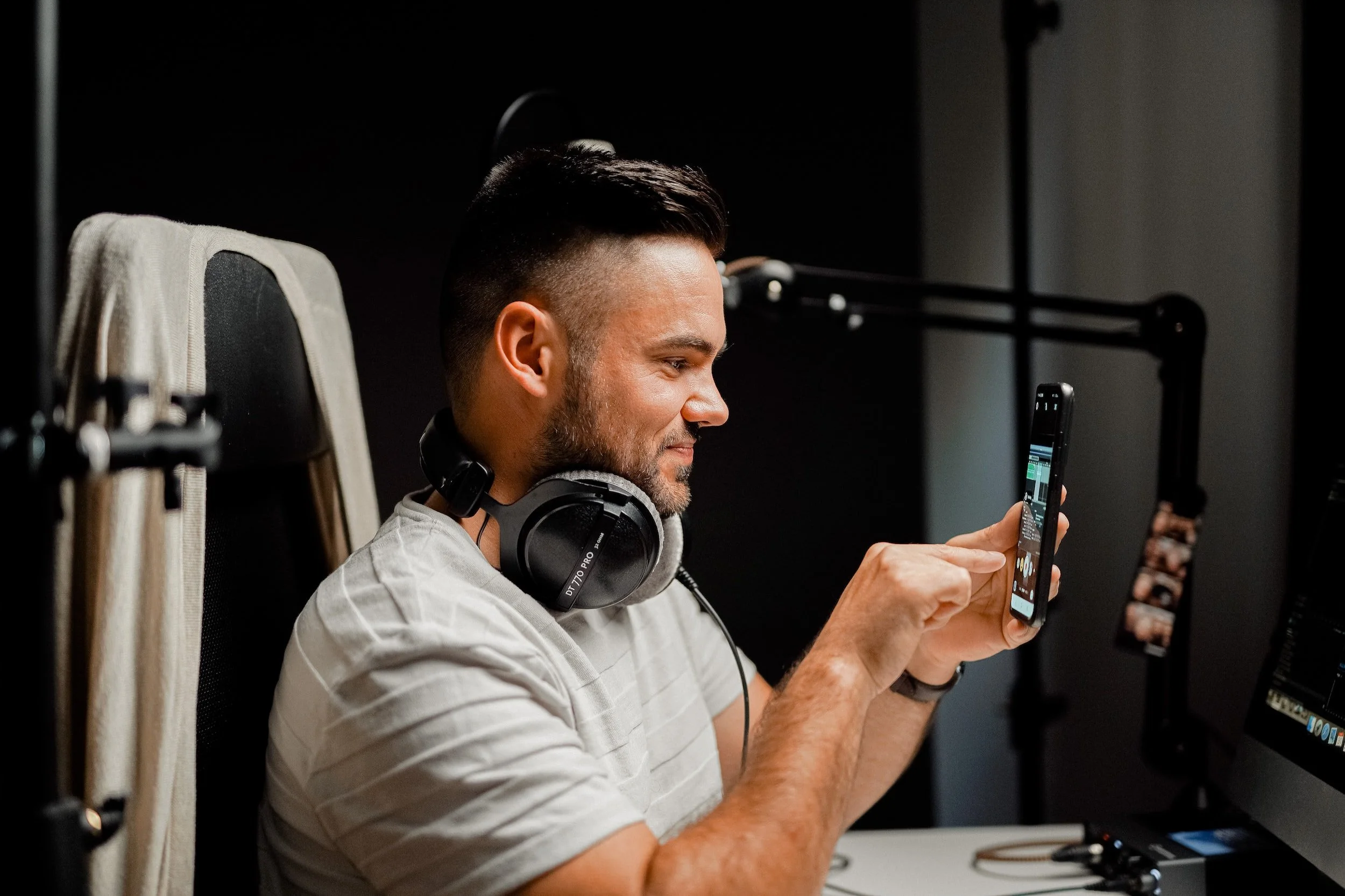 A content creator is wearing headphones and holding a phone to film himself.