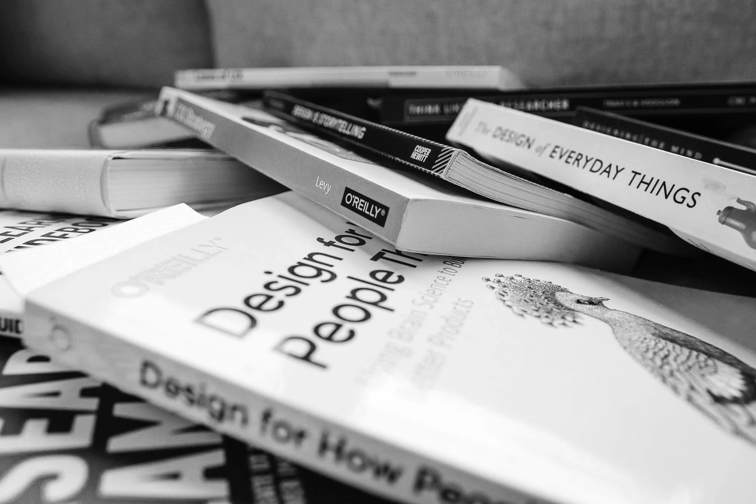 A pile of numerous design books including "Design for How People Think" and "The Design of Everyday Things."