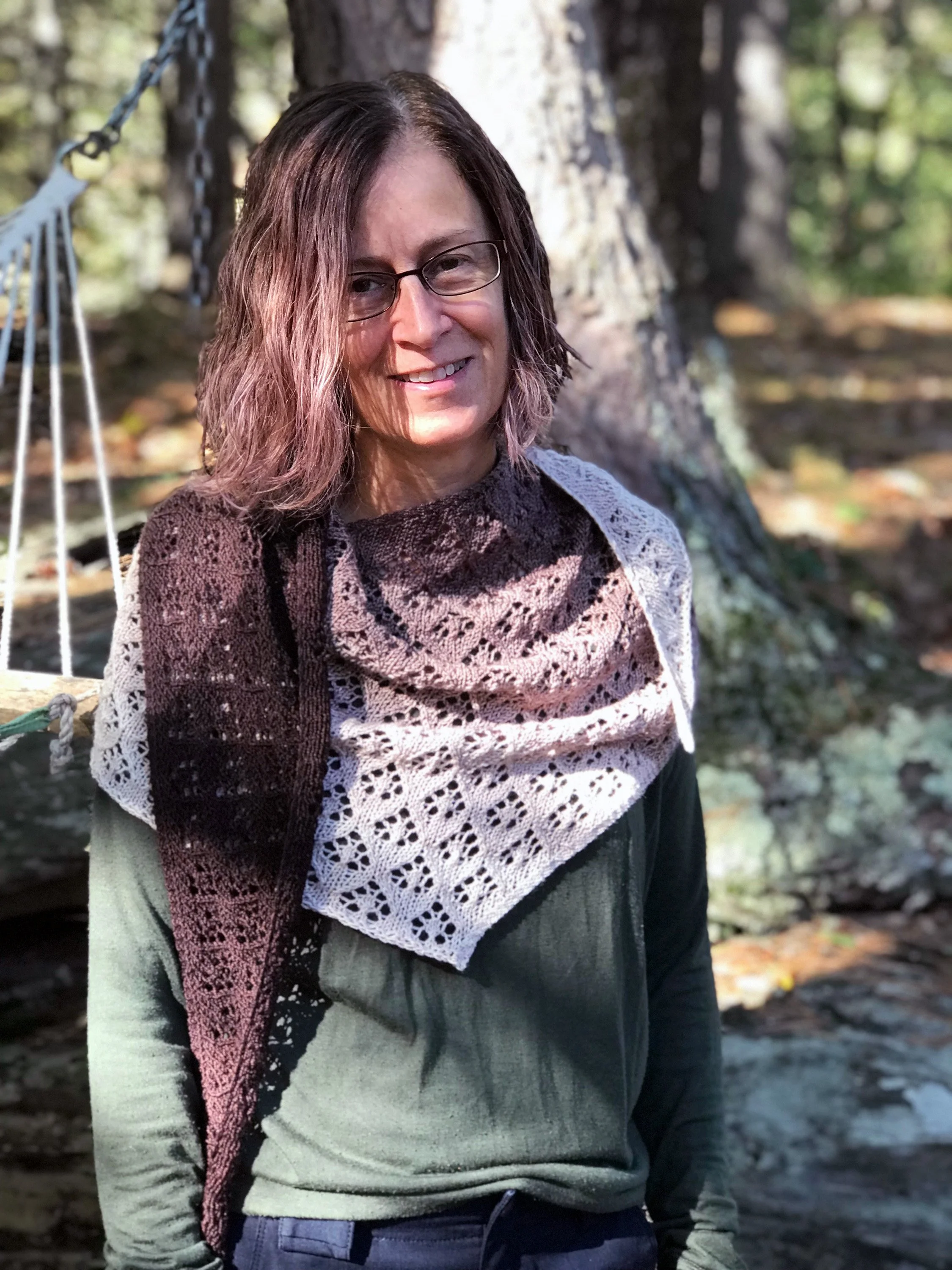 Woman modeling asymmetrical lace shawl, hand knit in a gradient of brown.
