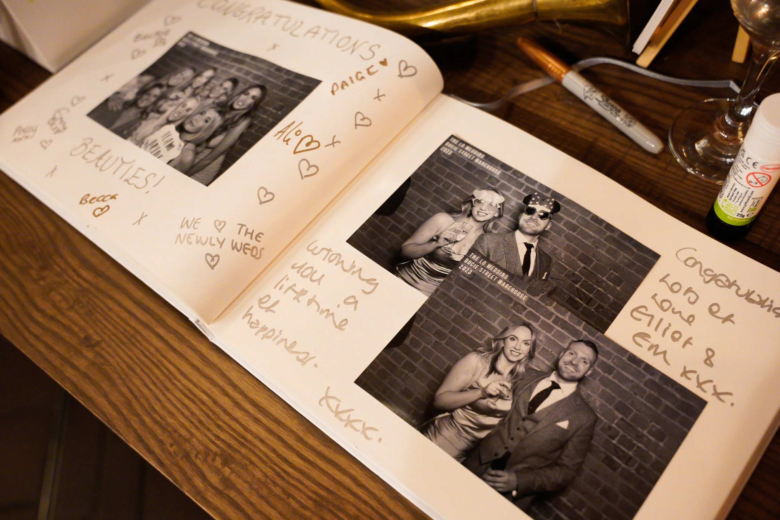 Open scrapbook with black-and-white photos of a wedding couple dressed with fun props, surrounded by handwritten notes and doodles.
