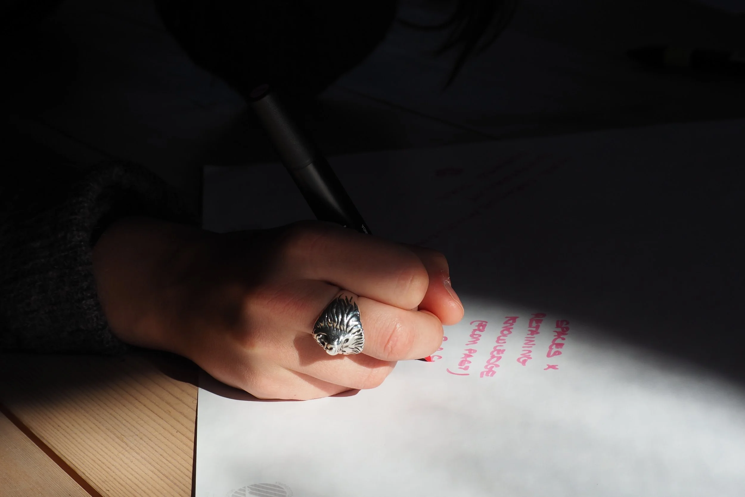 An athmospheric close-up of a hand writing on a paper in Embodied Transition Design Retreat.