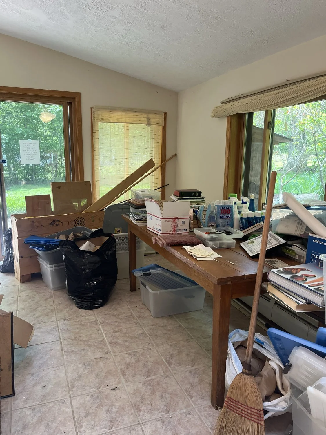 piles of art supplies and trash on tables in home art studio in Moreland Hills, Ohio before decluttering
