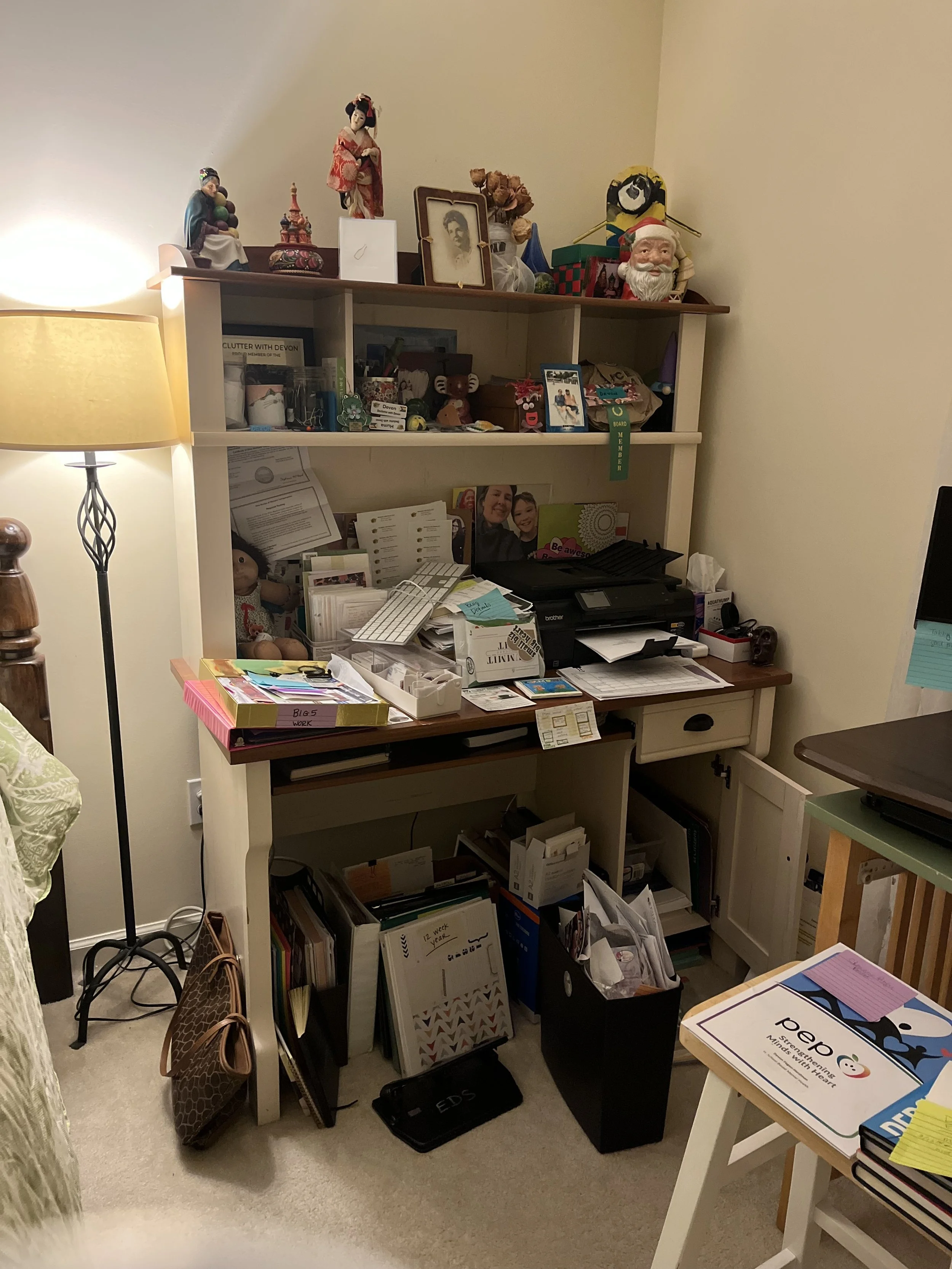 A picture of a desk with a hutch on it filled with papers and knickknacks on all surfaces and underneath it