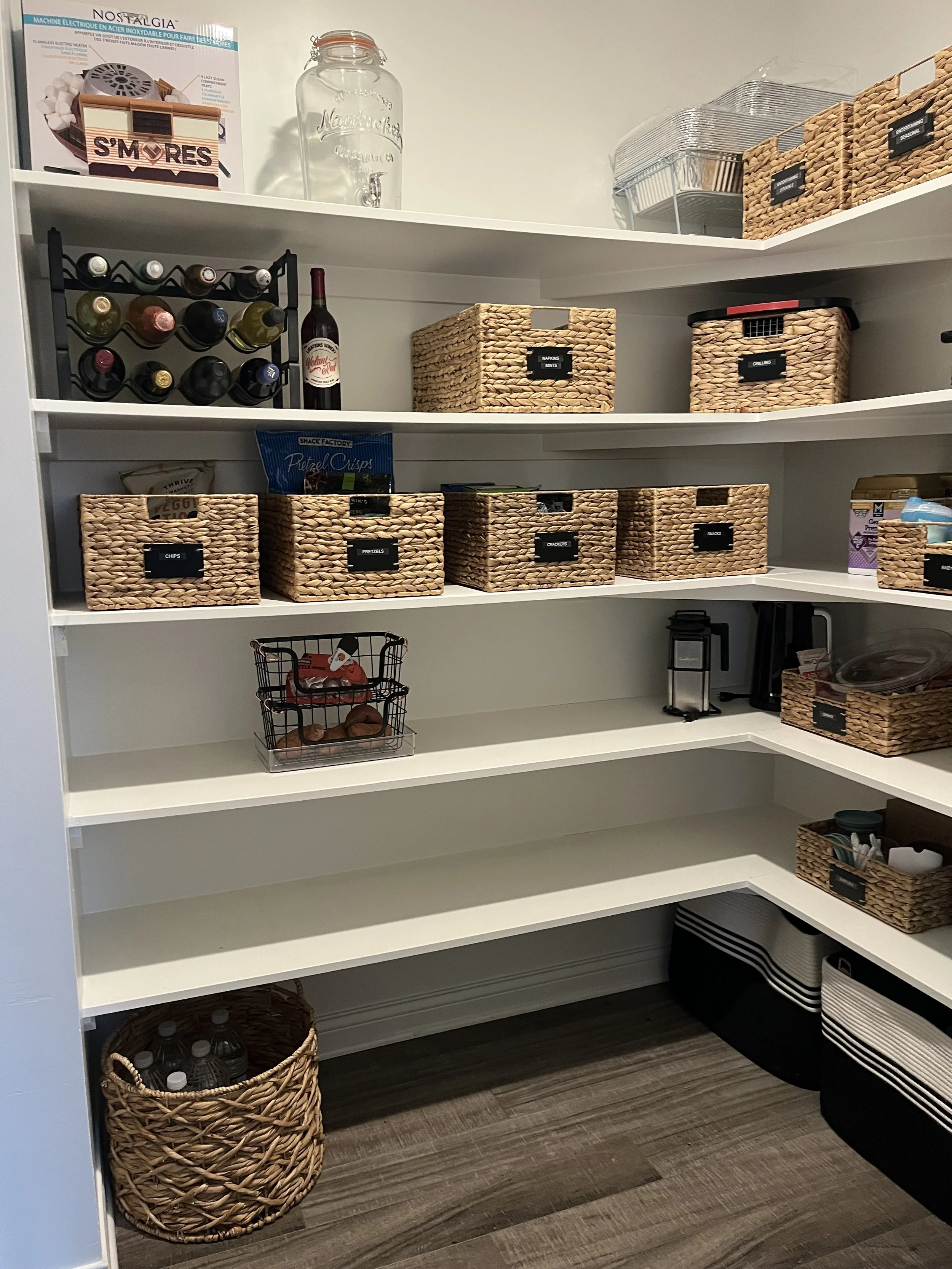 Organizing pantry showing empty shelves, matching wicker baskets, and a wine rack