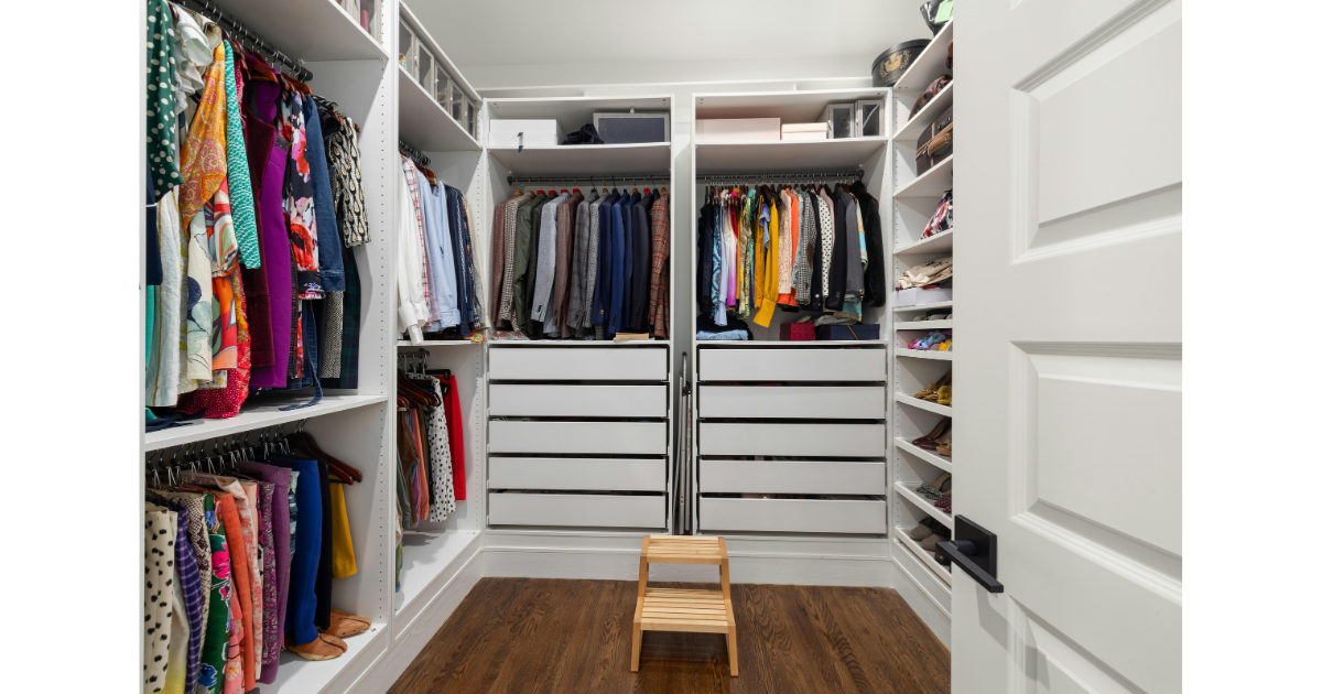 White built in shelving inside a closet with double hanging racks to the left, drawers with hanging suit coats and shirts above in the middle and shoes to the right