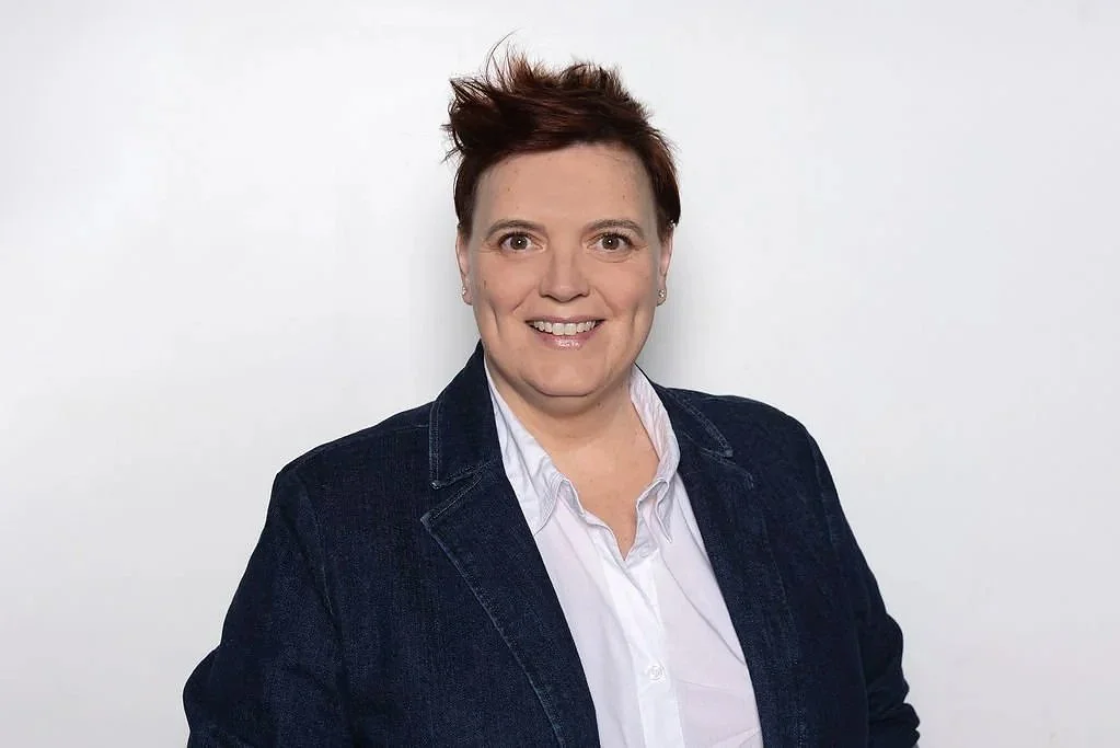 Roisin, a specialist behaviour consultant from Behaviour for Learning, smiling at the camera, wearing a white shirt and a dark blazer, against a plain white background.