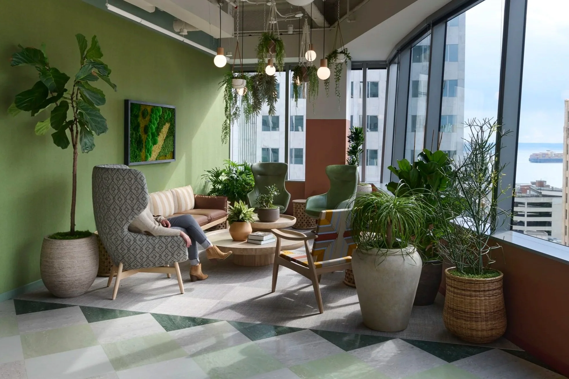 Biophilic space in modern office featuring plants, custom furniture, lighting and warm green hues