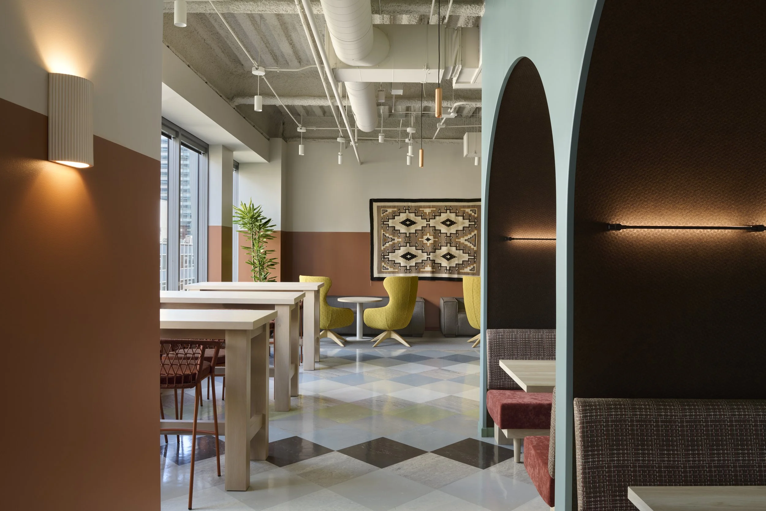 Modern workspace with multiple seating options including booths, tall tables, custom furniture areas and warm global design