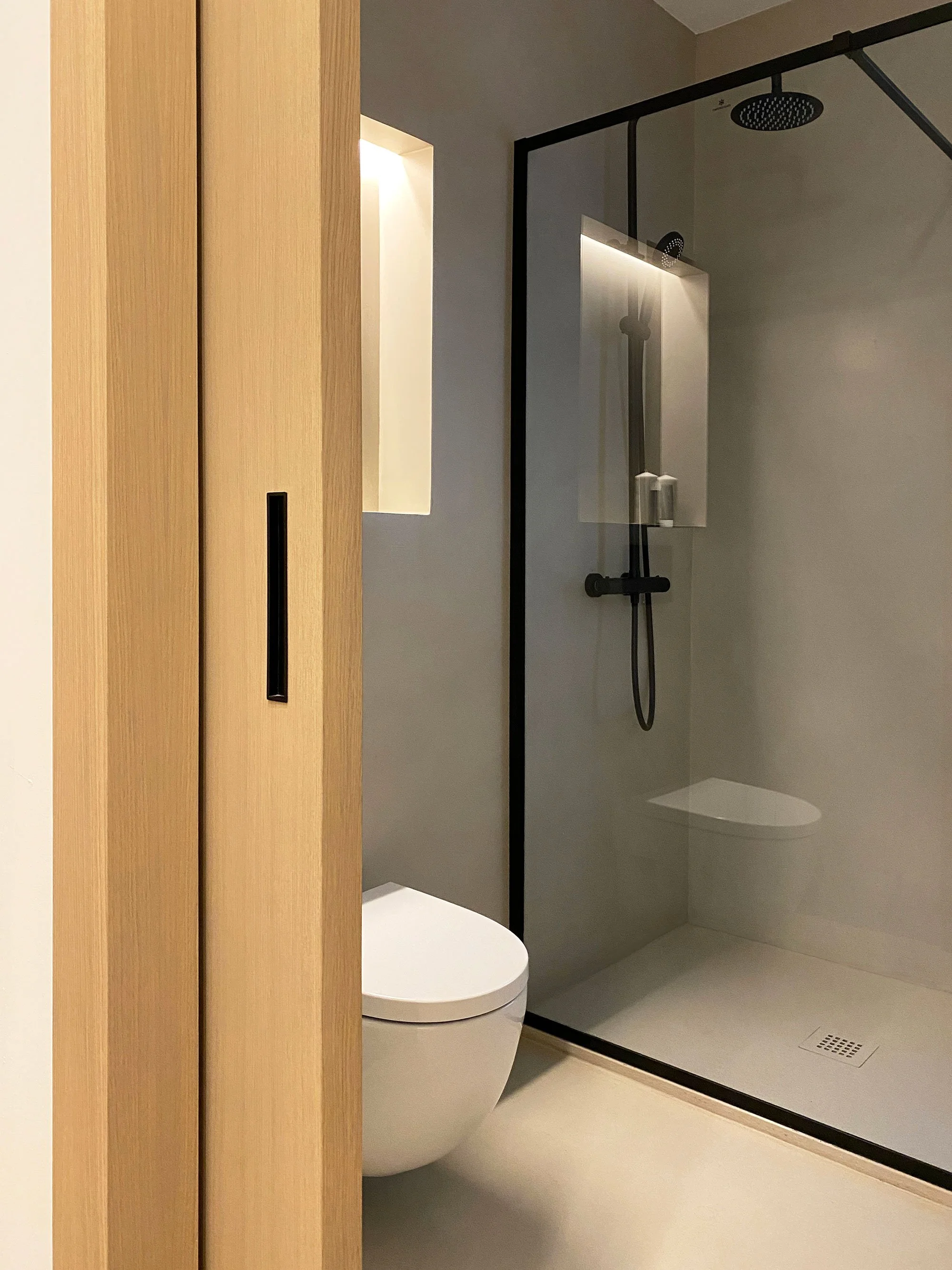 Contemporary bathroom in a renovated Barcelona apartment, featuring industrial minimalist interior design and bespoke detailing by MIA Studio.