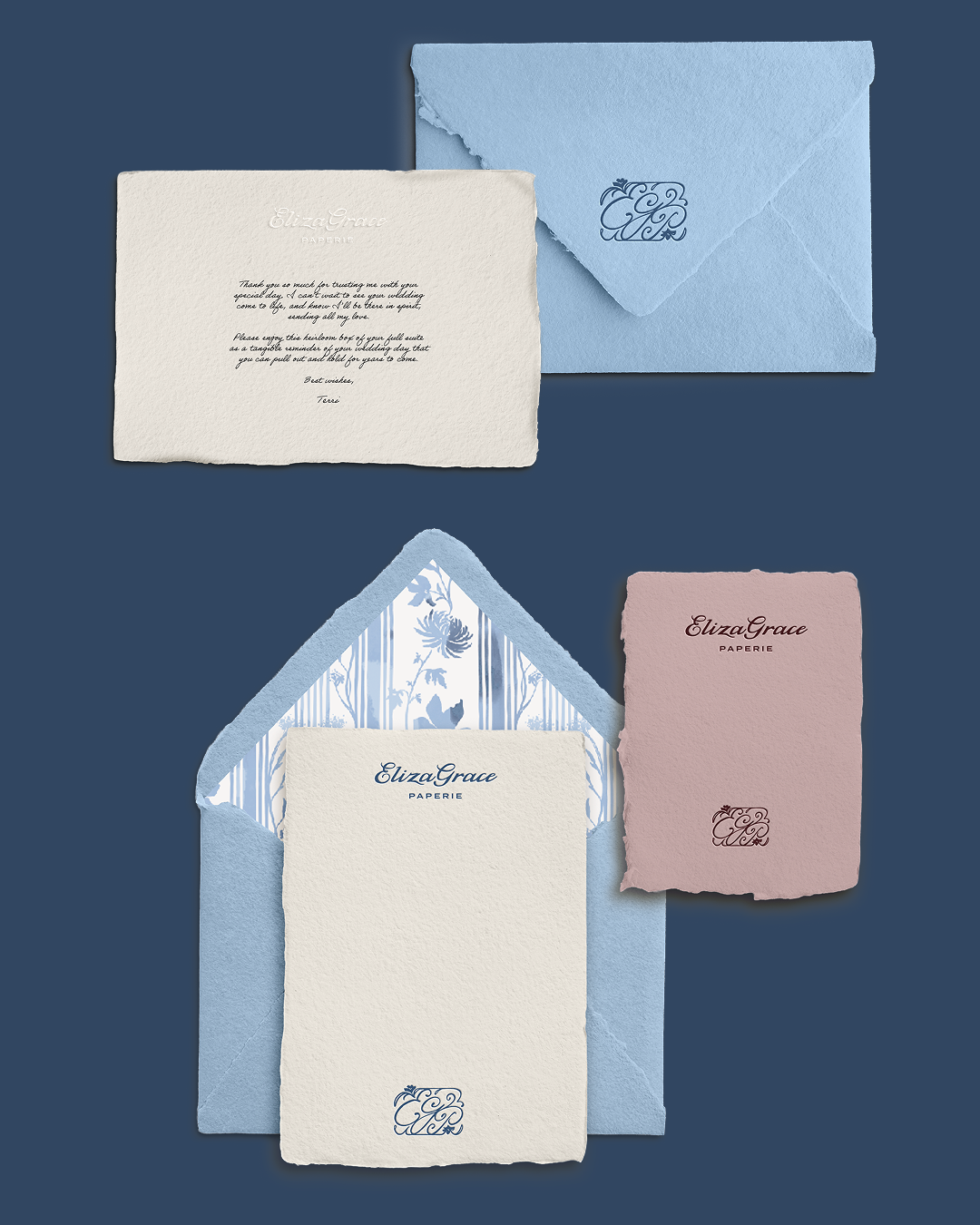 A flat lay of ElizaGrace Paperie stationery on a dark blue background, including textured blue envelopes—one with a floral interior—and cream and mauve cards featuring elegant typography, monogram logos, and a printed thank‑you note.