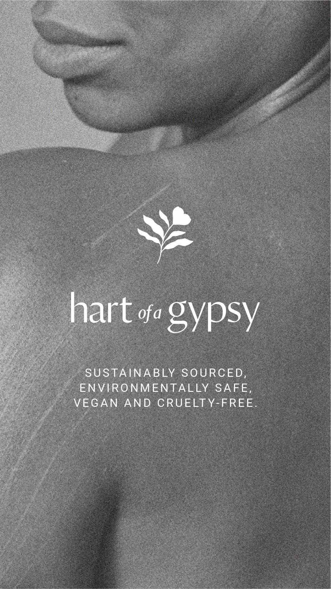 Grayscale close‑up of a person’s shoulder with overlaid text reading “hart of a gypsy — sustainably sourced, environmentally safe, vegan and cruelty‑free,” accompanied by a small plant icon.