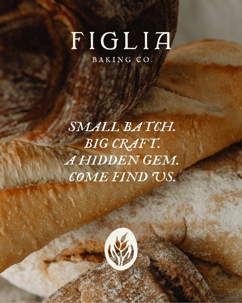 A close arrangement of rustic baguettes and round loaves dusted with flour. Overlaid white text reads “Figlia Baking Co. — Small batch. Big craft. A hidden gem. Come find us,” with a small wheat emblem below.