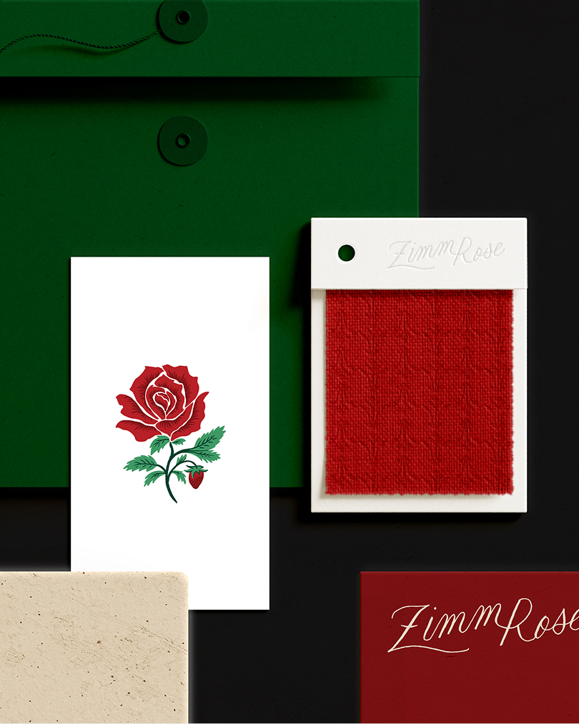 A flat lay arrangement of ZimmRose brand materials including a green envelope, illustrated rose card, red fabric swatch card, beige paper sample, and a dark red card with the ZimmRose script logo.