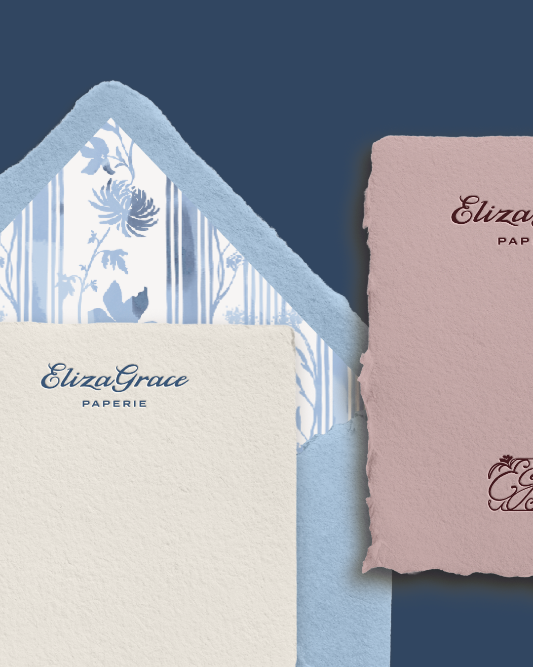 Two textured stationery sheets—one cream with blue ElizaGrace Paperie branding and one mauve with red branding—paired with a light blue envelope featuring a blue-and-white floral striped interior, showcasing cohesive paper goods design.