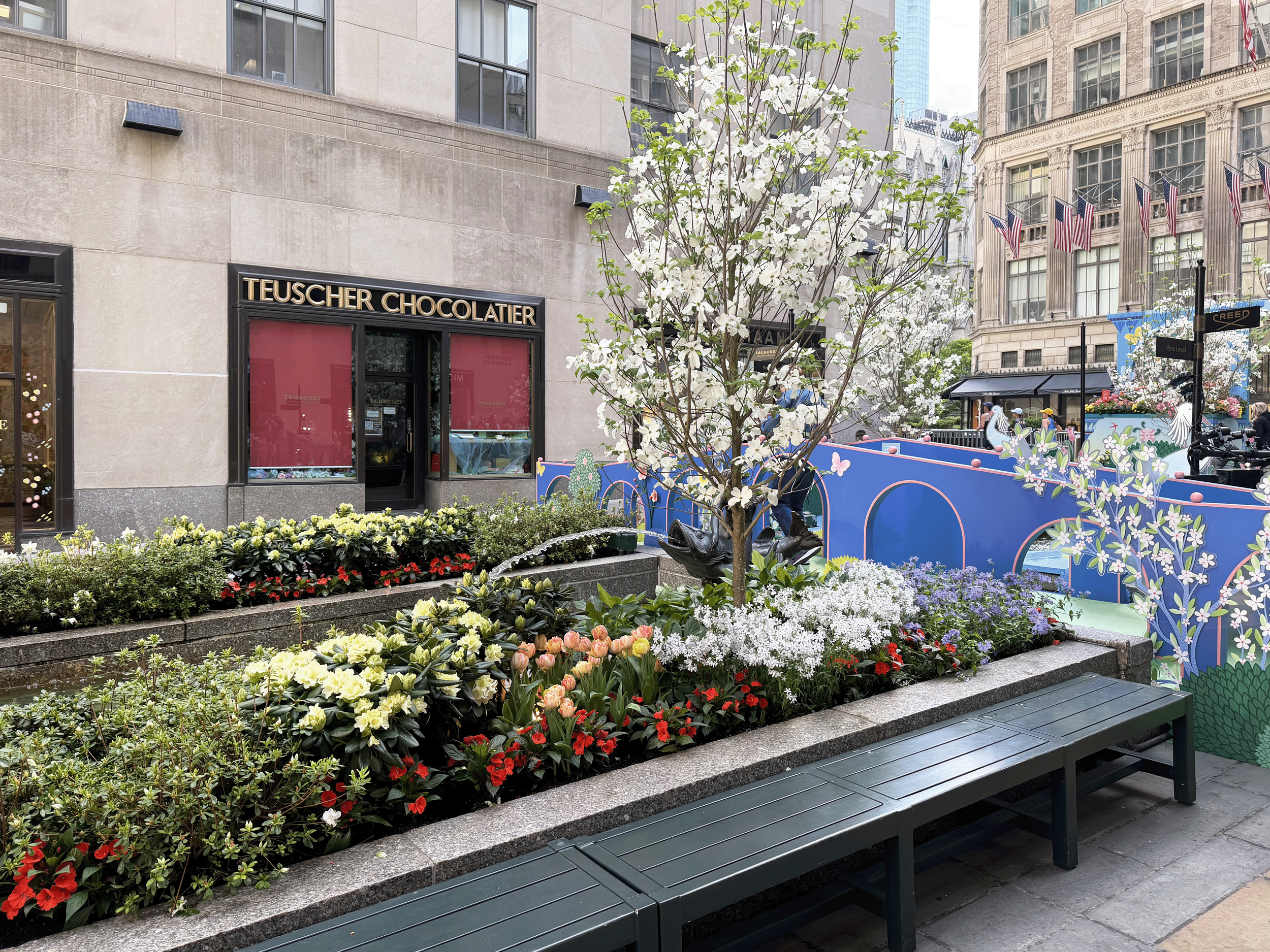 Channel Gardens at Rockefeller Center contains beautiful flower beds, trees, statues, and a marble fountain, surrounded by historical high-rise buildings in the heart of NYC. 