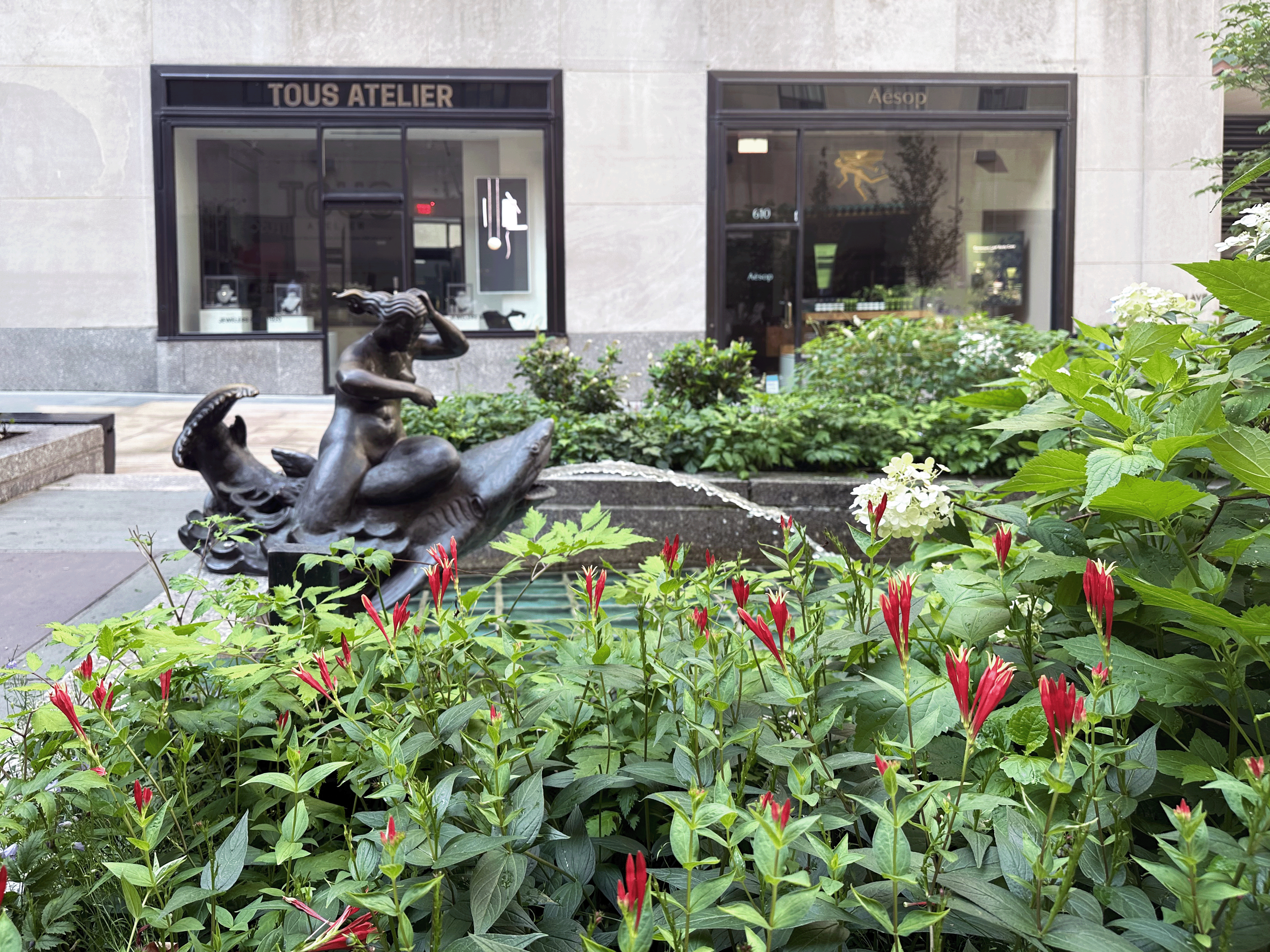 Channel Gardens at Rockefeller Center contains beautiful flower beds, trees, statues, and a marble fountain, surrounded by historical high-rise buildings in the heart of NYC. 