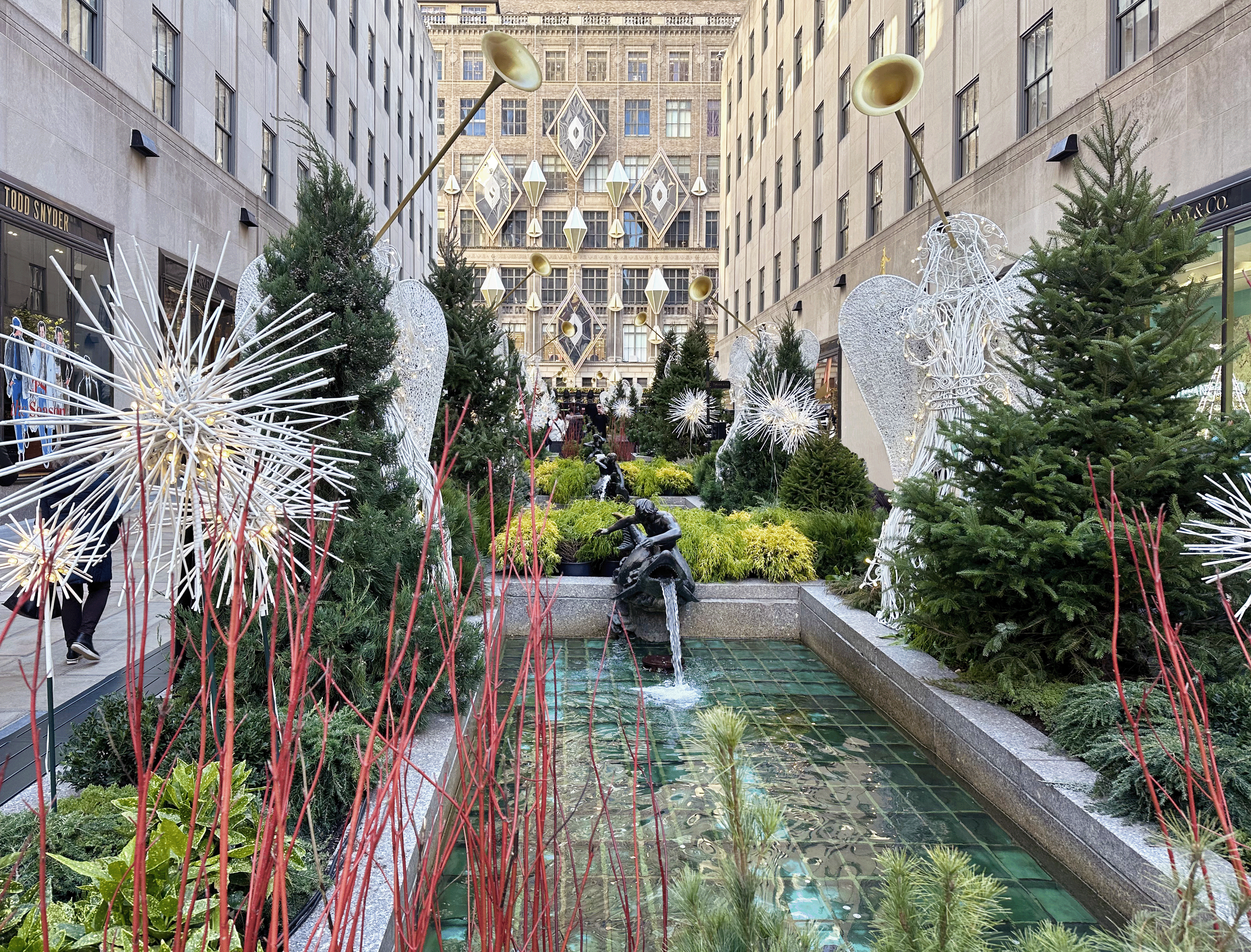 Channel Gardens at Rockefeller Center contains beautiful flower beds, trees, statues, and a marble fountain, surrounded by historical high-rise buildings in the heart of NYC. 