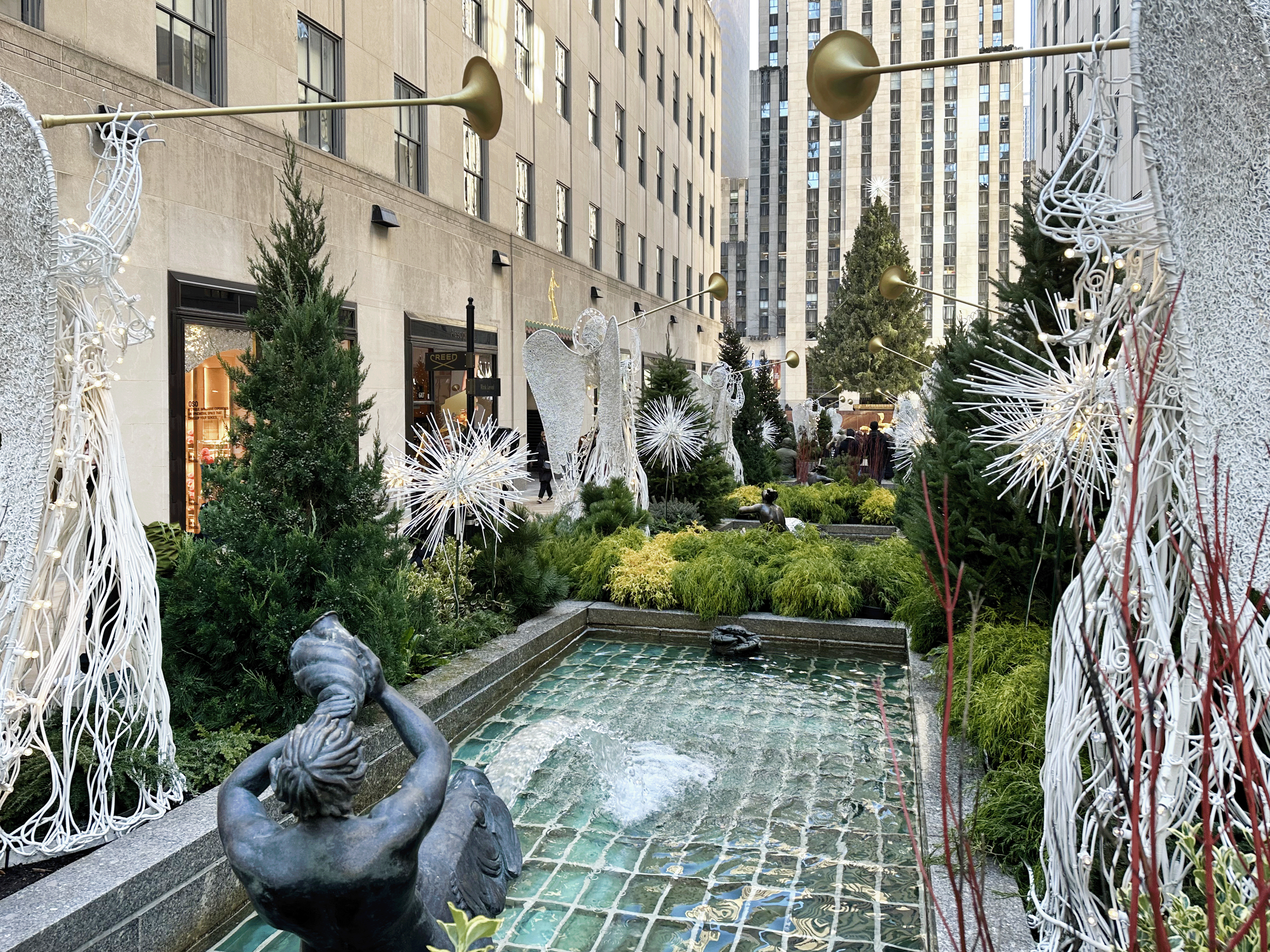 Channel Gardens at Rockefeller Center contains beautiful flower beds, trees, statues, and a marble fountain, surrounded by historical high-rise buildings in the heart of NYC. 