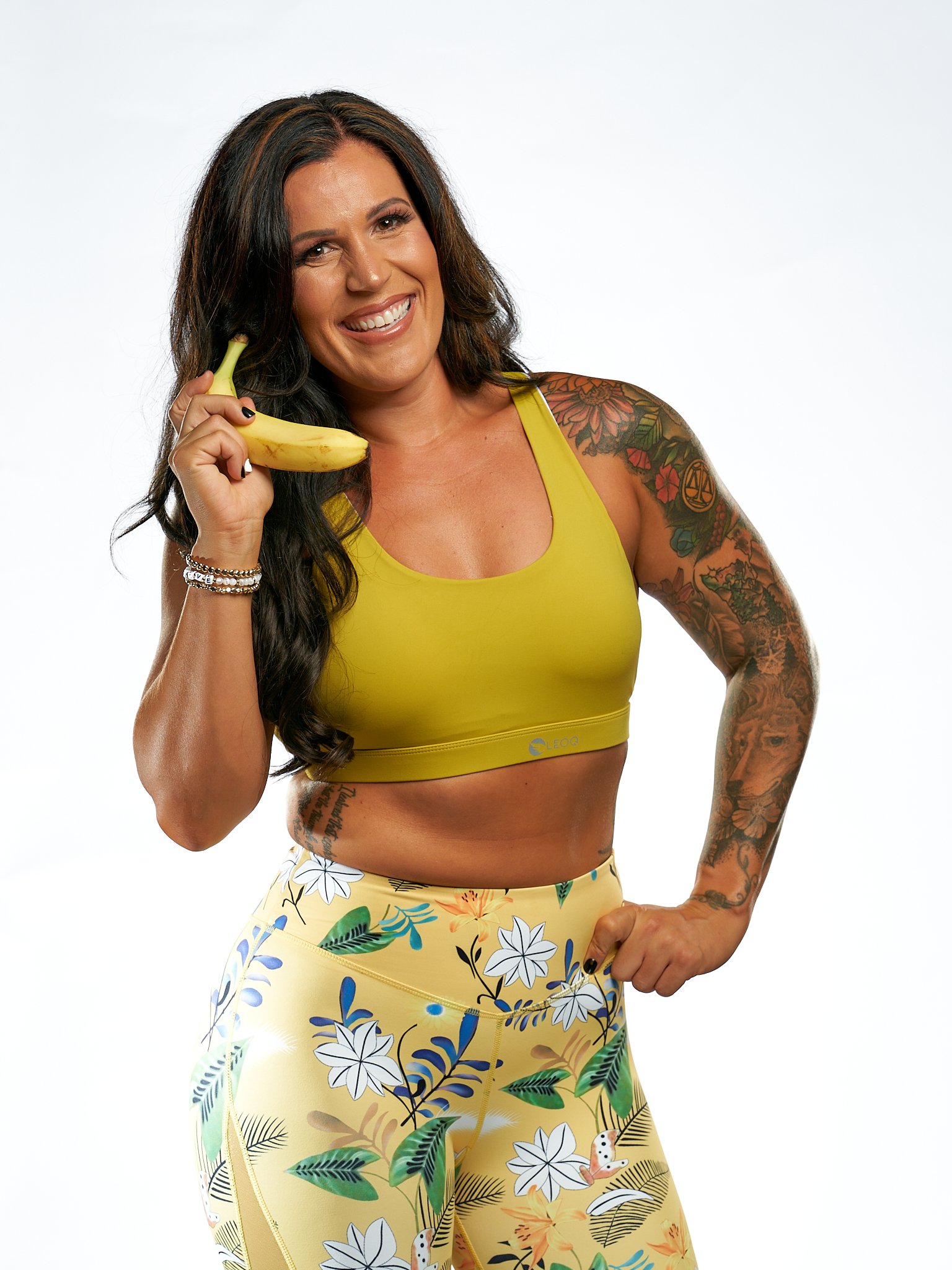  Fitness Model dressed in yellow posing with a banana like a telephone during her fitness photoshoot to relate that she is also a nutritionist.  
