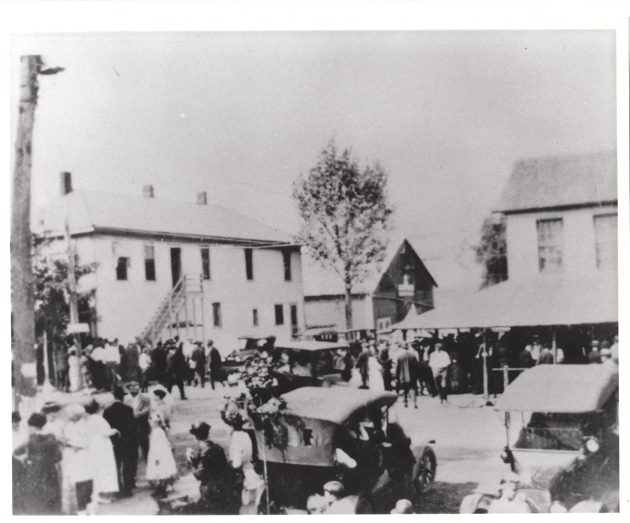 Black and white photo of a Labor Day gathering in Pickerington around 1920, showing a crowd of residents, early automobiles, and buildings along Columbus Street.