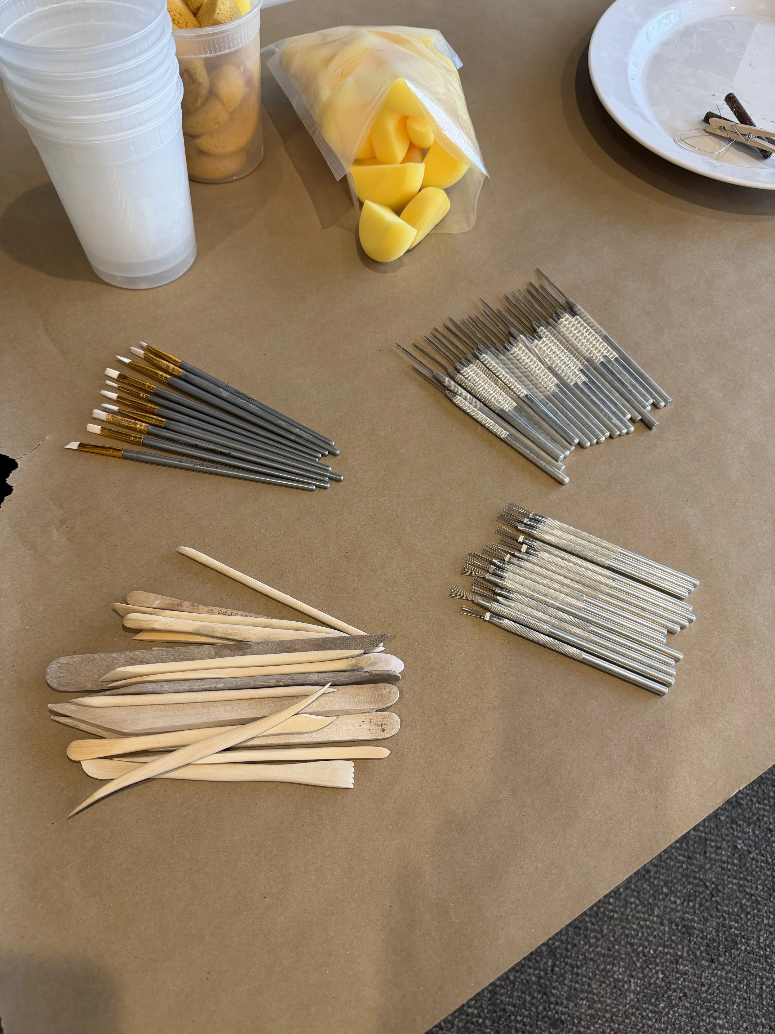 Assorted dental tools including dental probes, scaler, and scraping tools arranged on a table, with a plate, peeled potatoes, cheese, and jars of cookies in the background.
