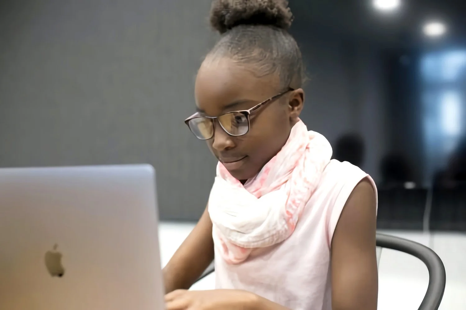Young girl with glasses working at computer screen