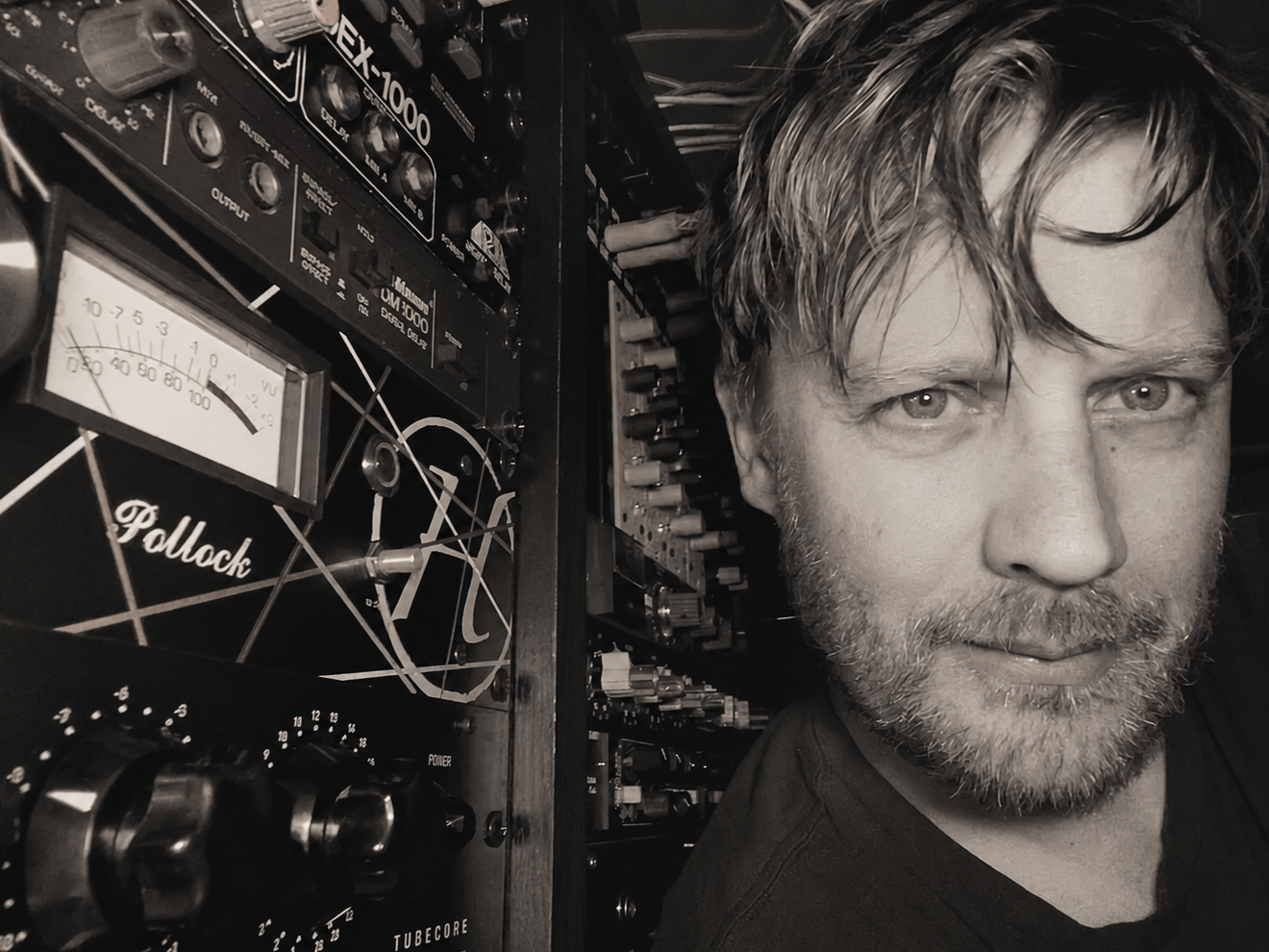Scott Ecklein in his studio beside analog audio equipment in 2026.