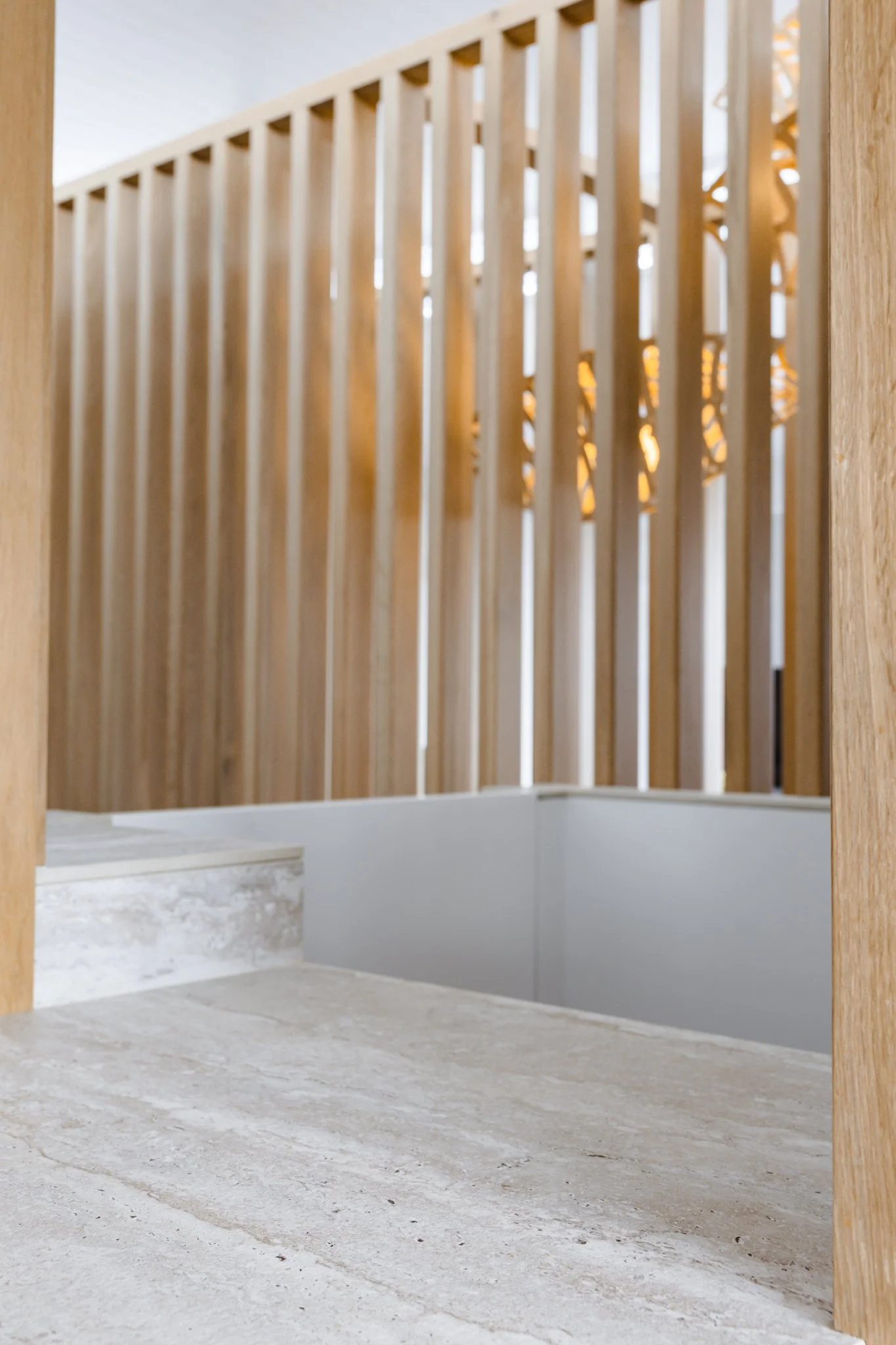 Interior view of a building under construction, showing a carpeted floor, a wooden railing with vertical slats, and a small staircase to the left, with unfinished walls and open space.
