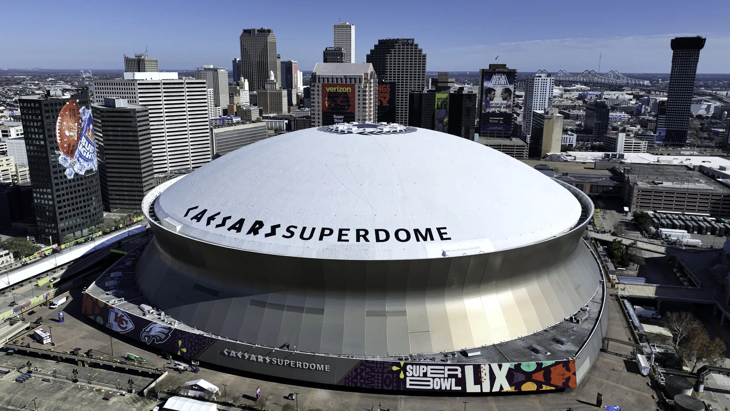 Aerial view of Caesars Superdome in New Orleans, Louisiana, with the city skyline and tall buildings in the background.