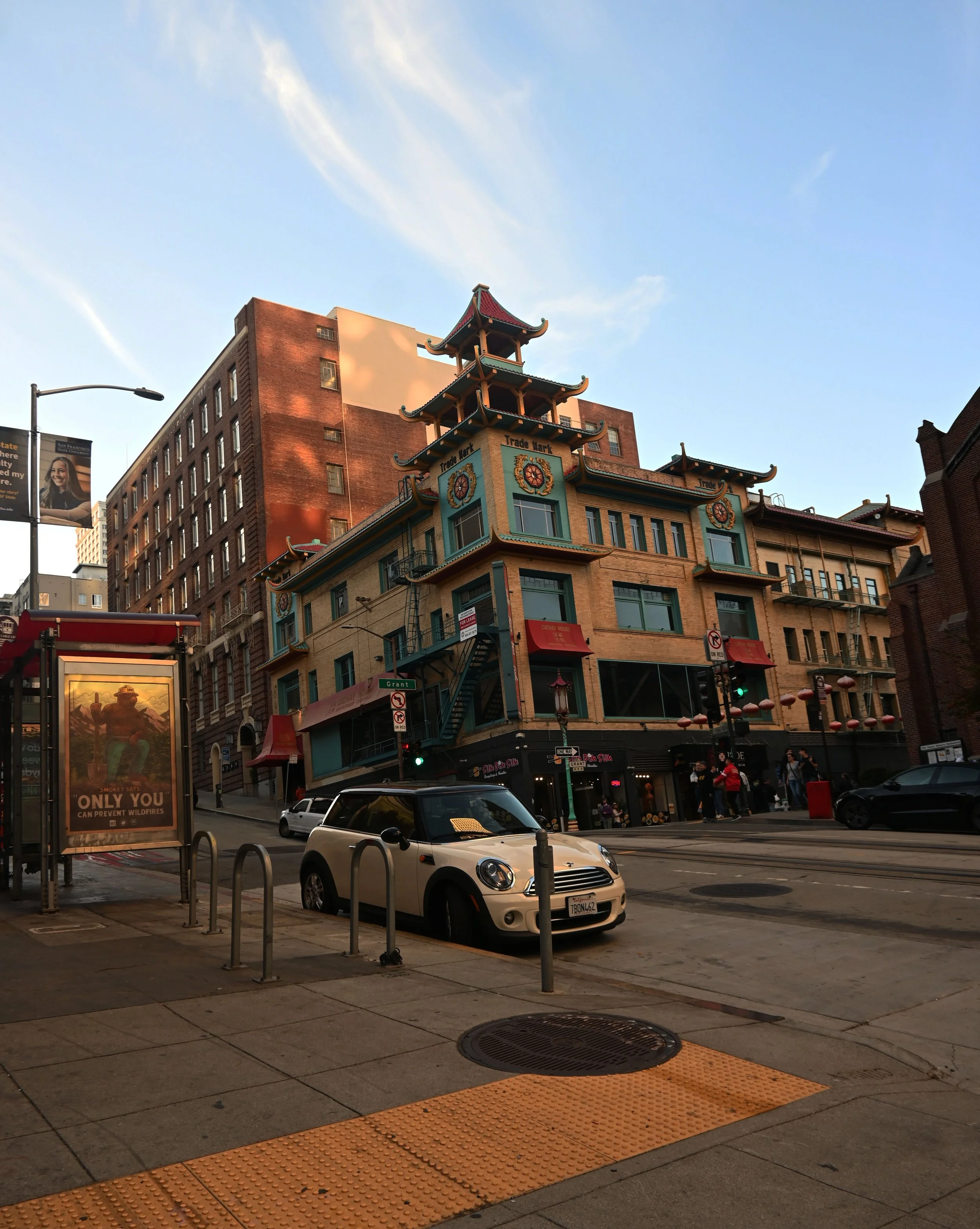 Street scene with a traditional Chinese-style building named 'Trade Mark' in San Francisco, California, with cars, pedestrians, and a bus stop.