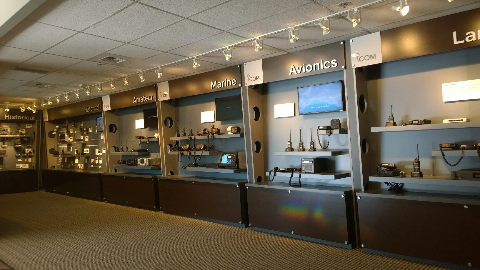A long wall is divided into sections: "Historical," "Amateur," "Marine," and "Avionics." All sections feature a timeline of radios, represented in photos or displayed on shelves.