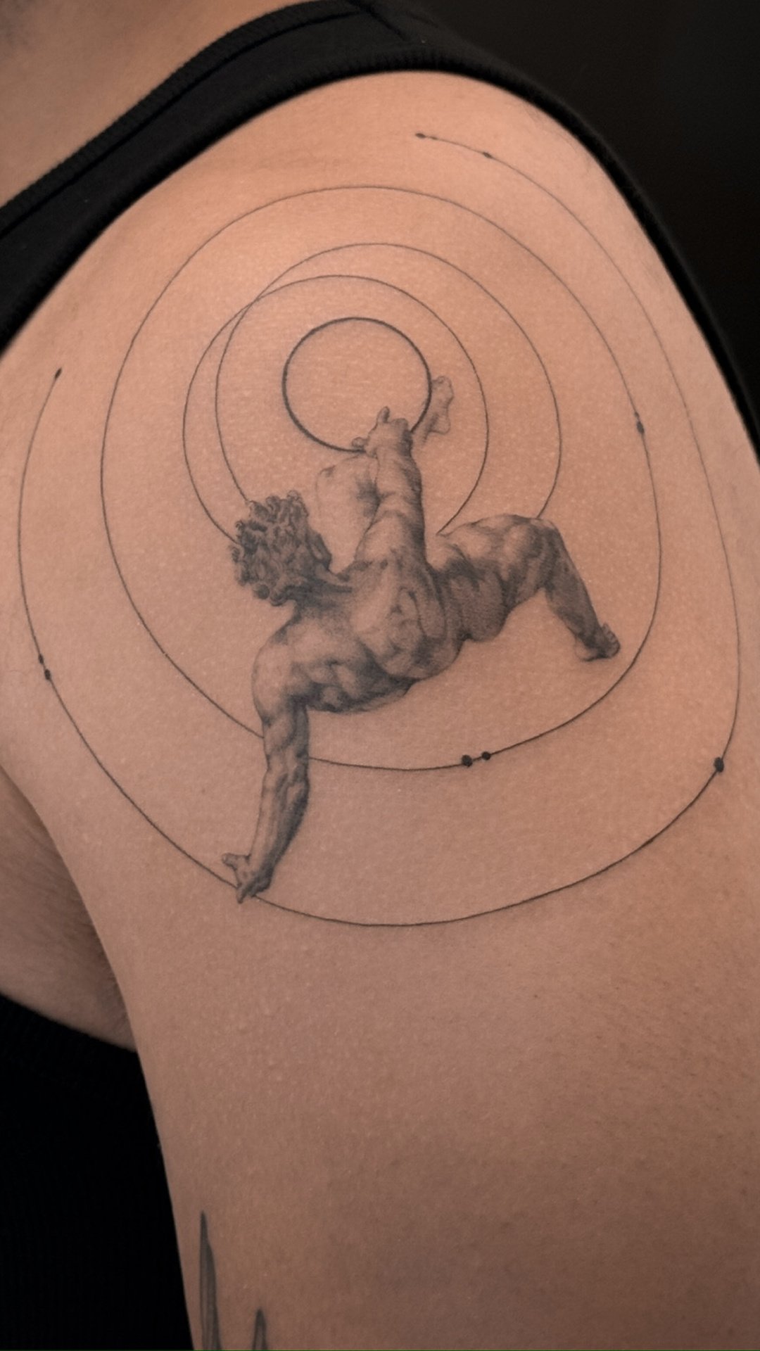 A tattoo of a muscular lion holding a ball, with concentric circles and small dots surrounding it.