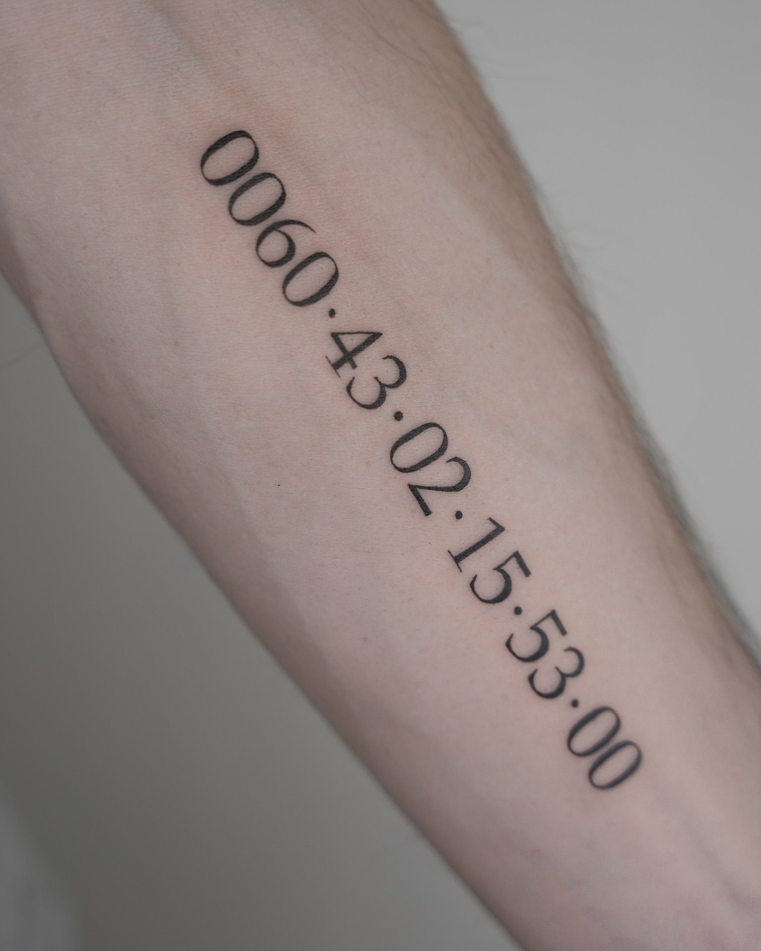 Tattoo of a GPS coordinates on person's arm.