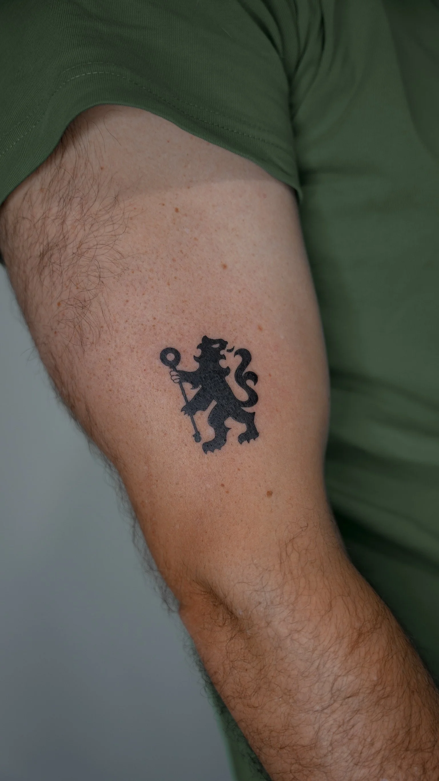 Tattoo of a black lion holding a scepter on a person's upper arm.