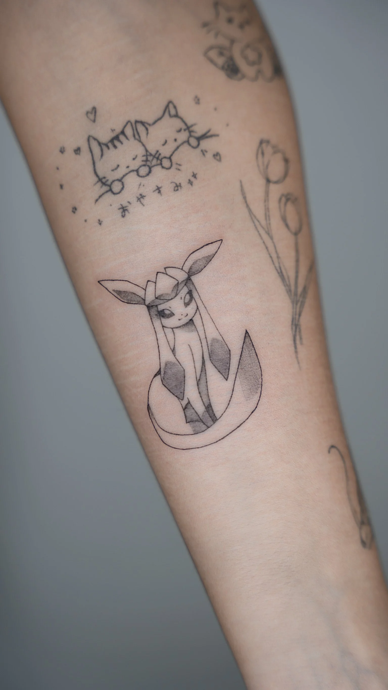 Tattoo of a cute, stylized fox with large ears and a long tail.