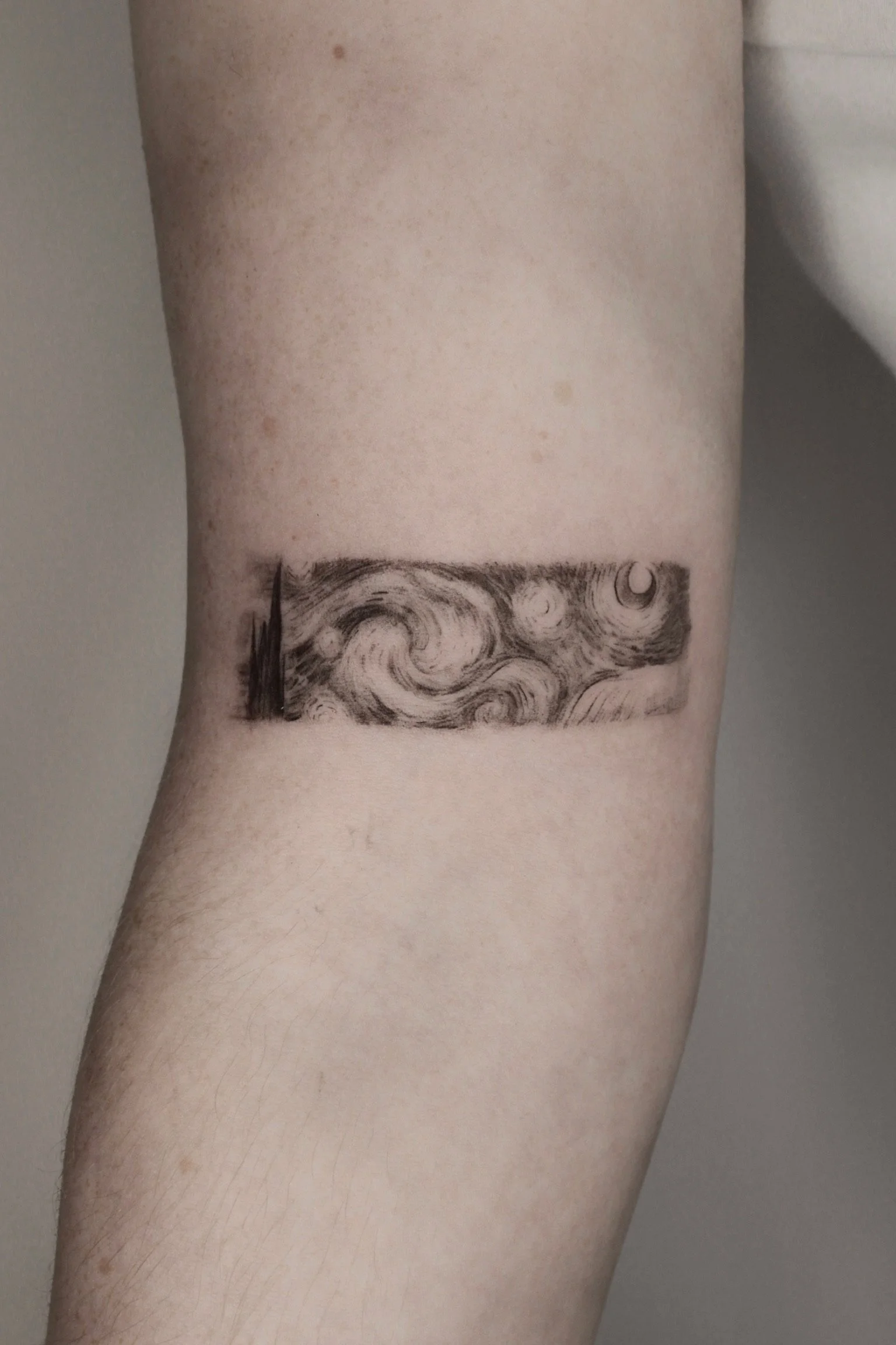 Tattoo of Vincent van Gogh's 'The Starry Night' on person's arm.