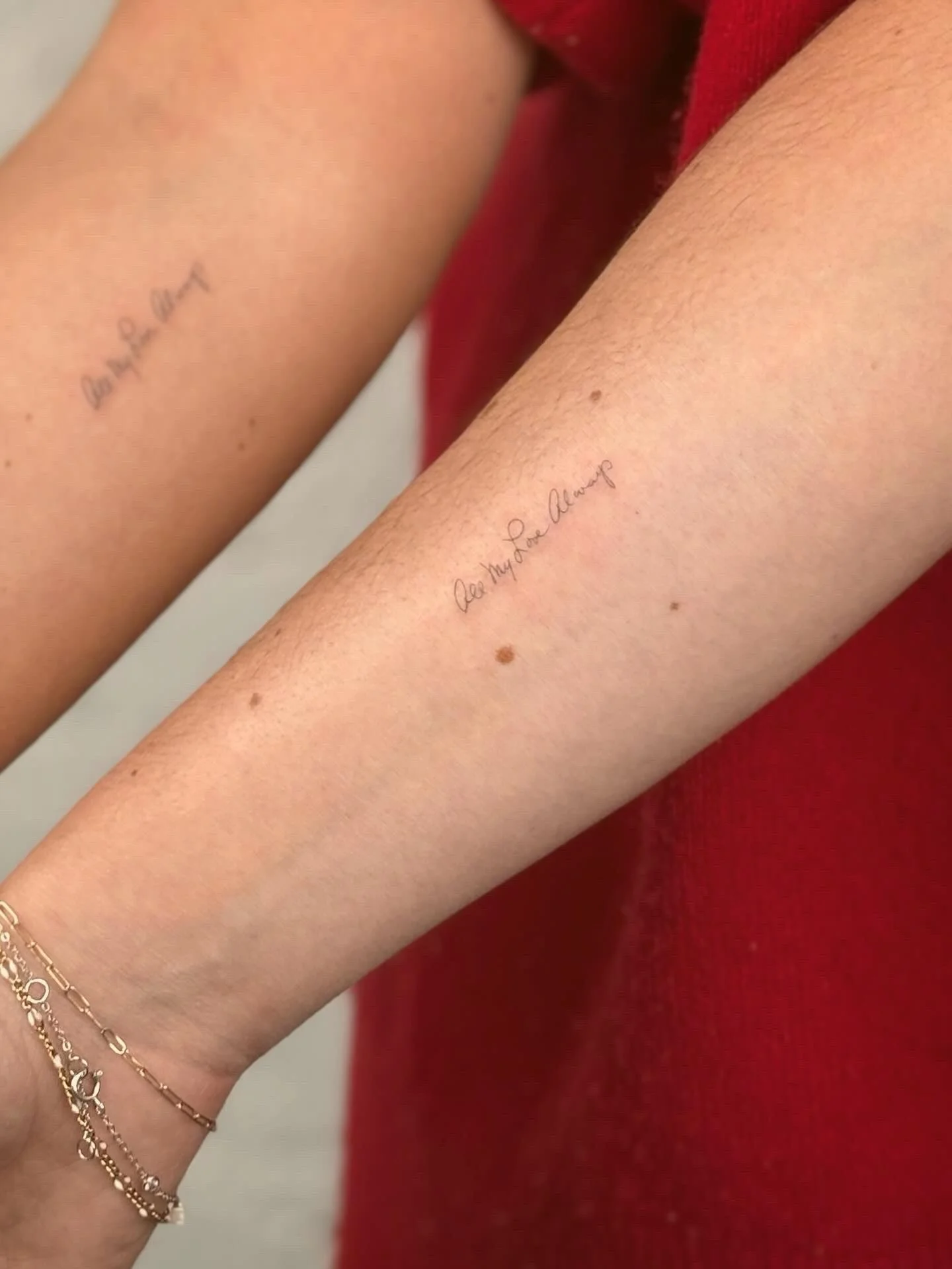 Matching tattoos of fineline script in SoHo, New York