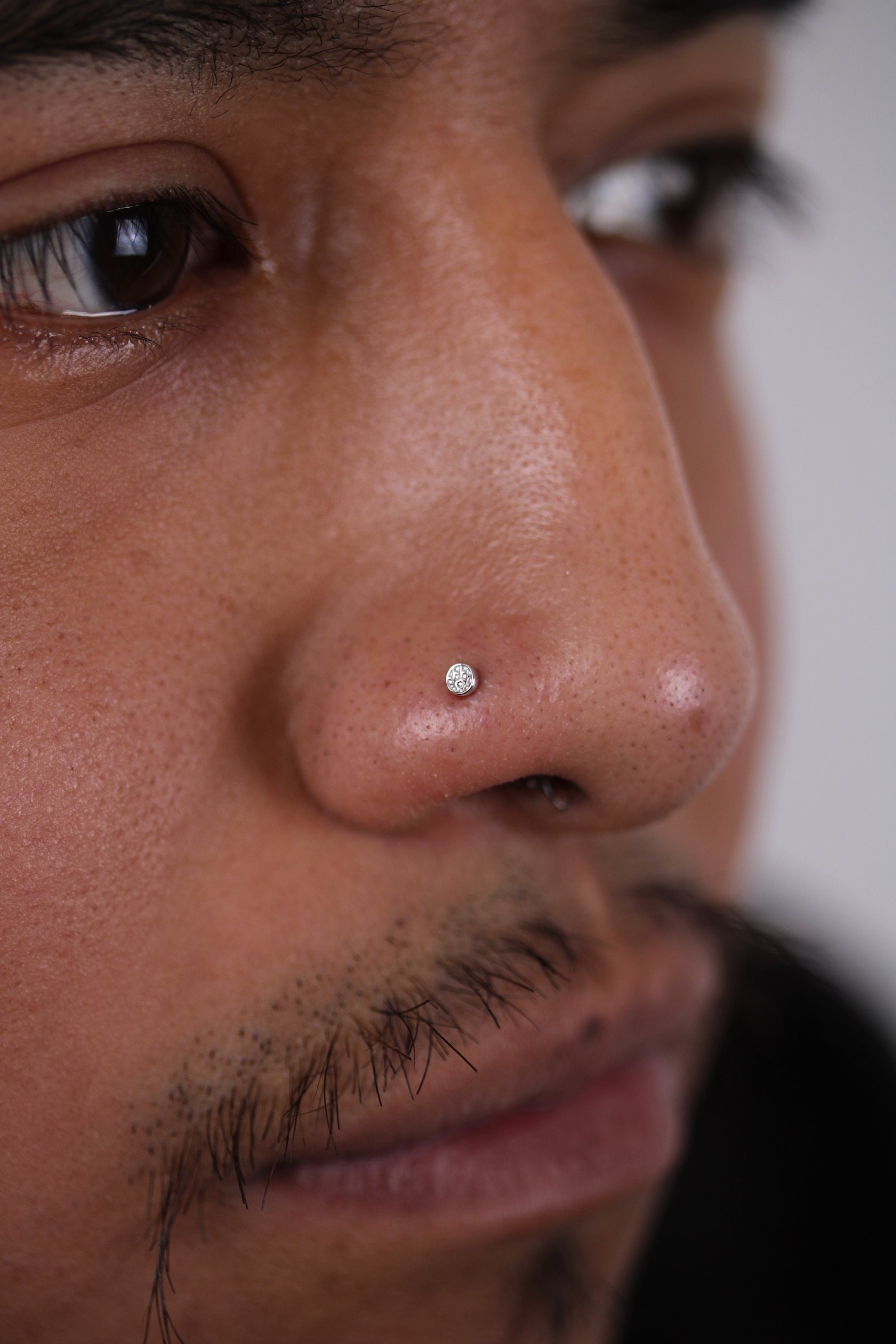 Close-up of a person's face showcasing a nose piercing with a small diamond stud.