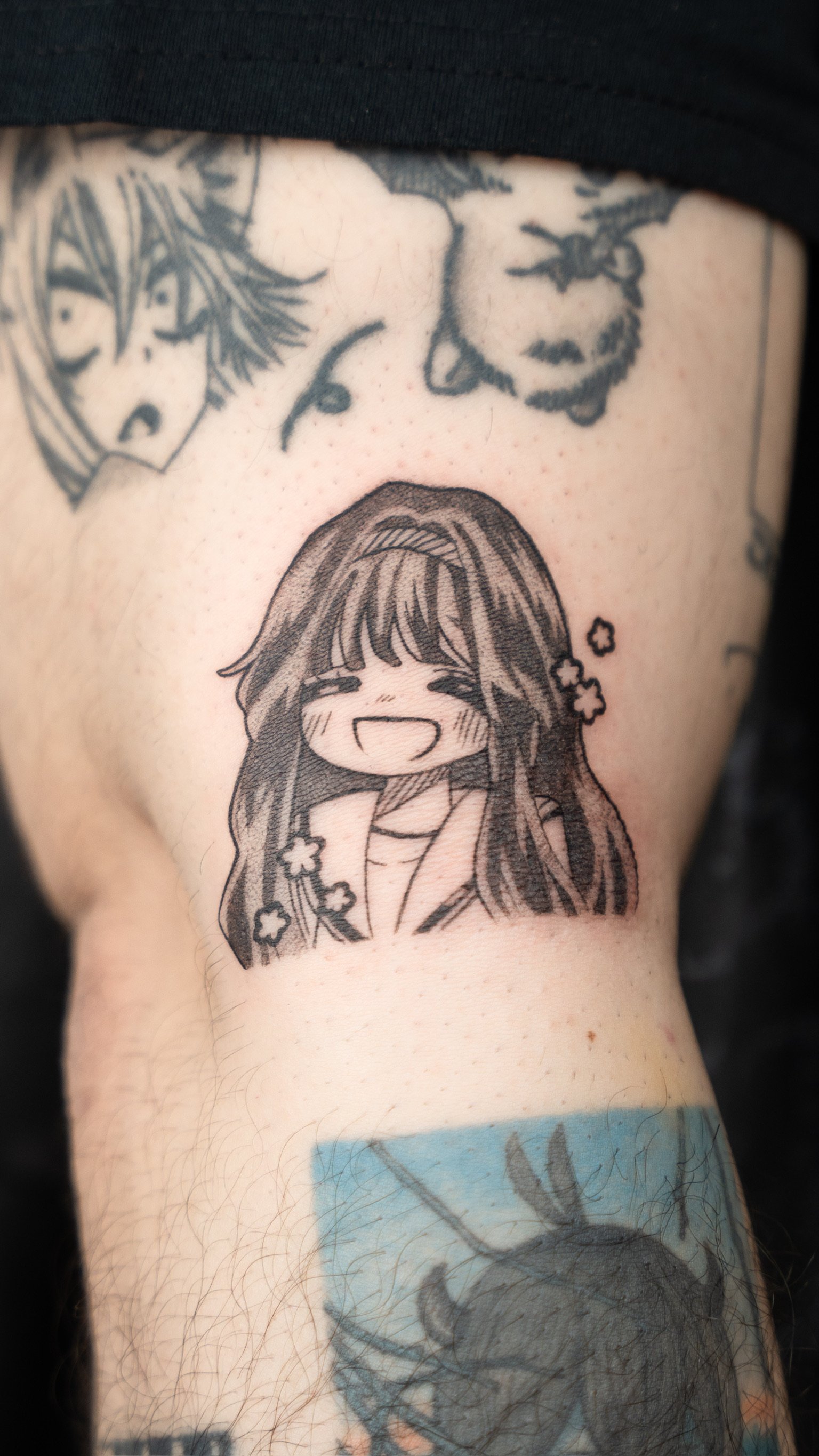 Tattoo of a smiling anime girl with long hair and flower accessories.