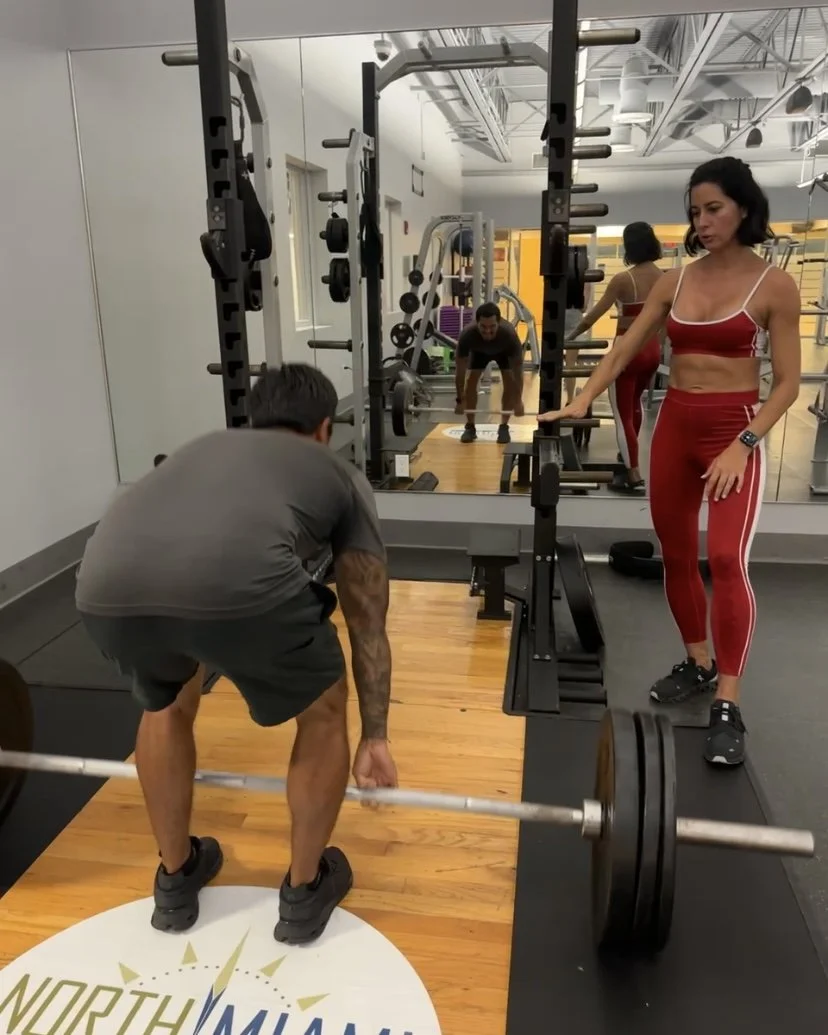 Trainer coaching barbell deadlift technique during strength session
