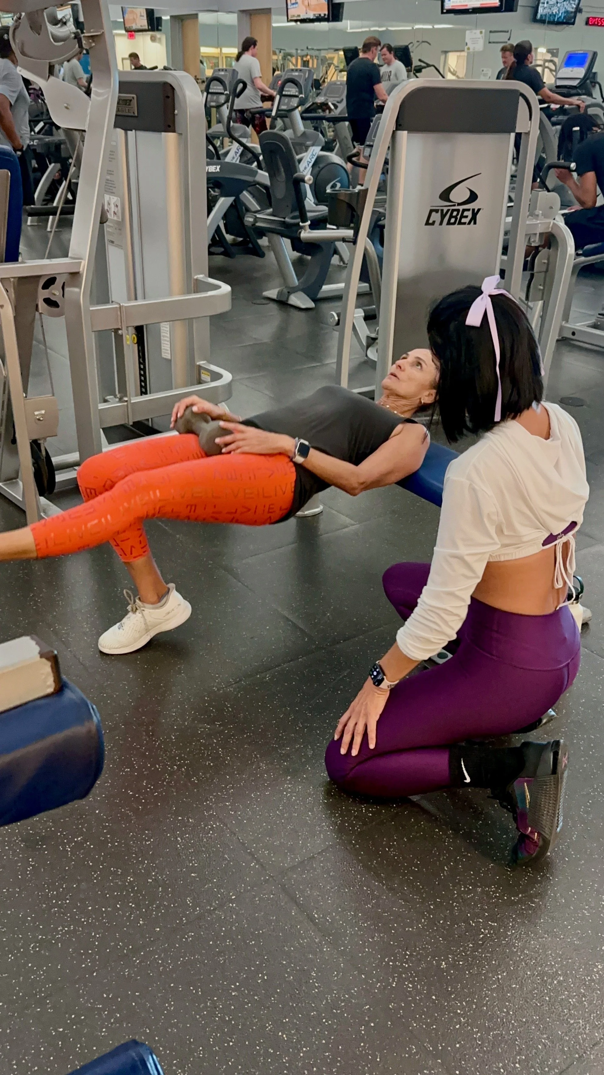 Client performing single leg hip thrust with trainer guidance for strength training